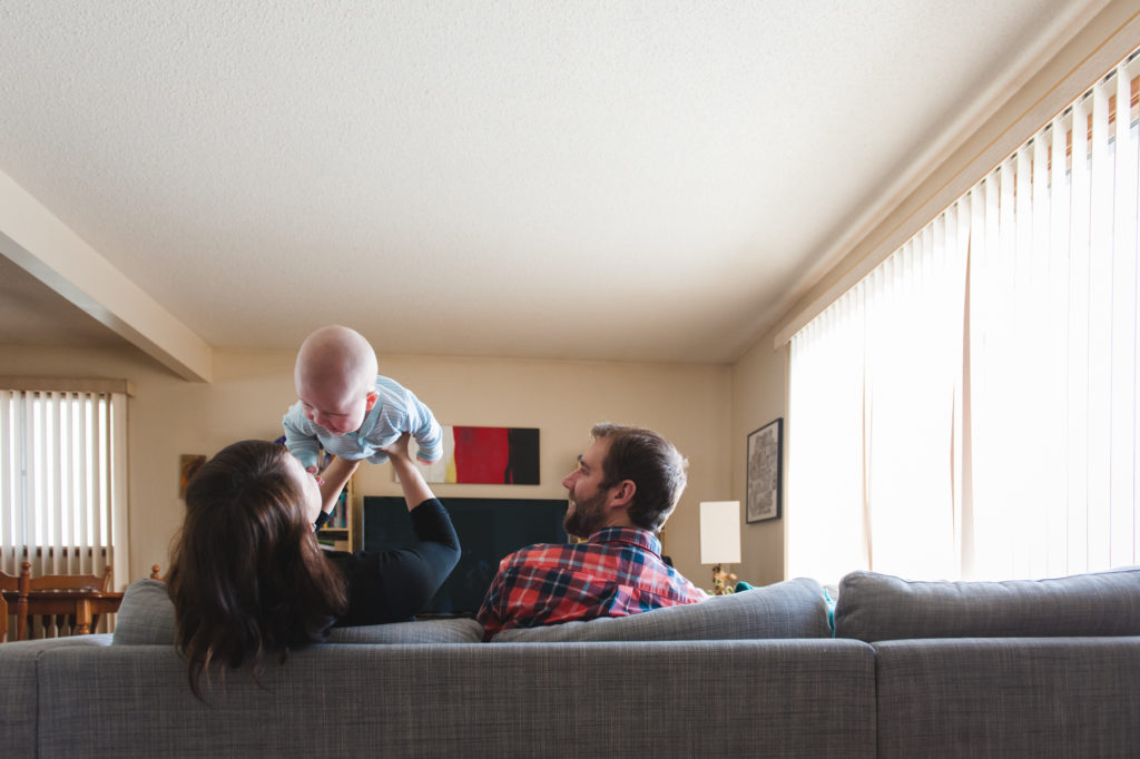 Mom and dad playing airplane with 6 month baby in photo session by Edmonton photographer Fiddle Leaf Photogrpahy