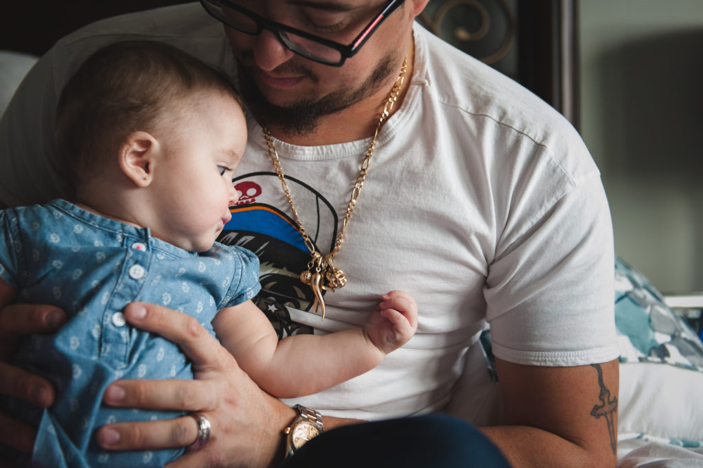 6 month old baby looks at Dad's jewelry. 6 month baby photos by Edmonton Photographer Fiddle Leaf Photography.