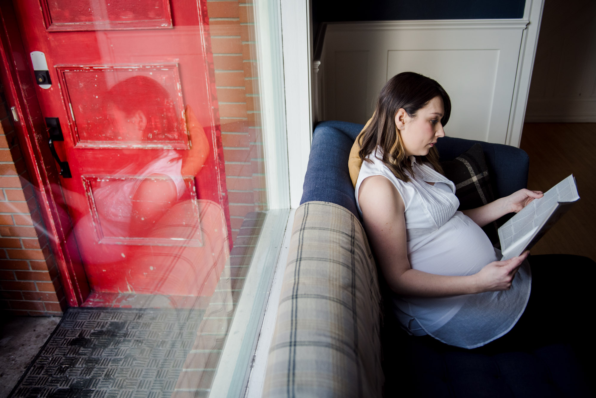 A pregnant woman reads a magazine featuring clothing from Yo Mama Maternity
