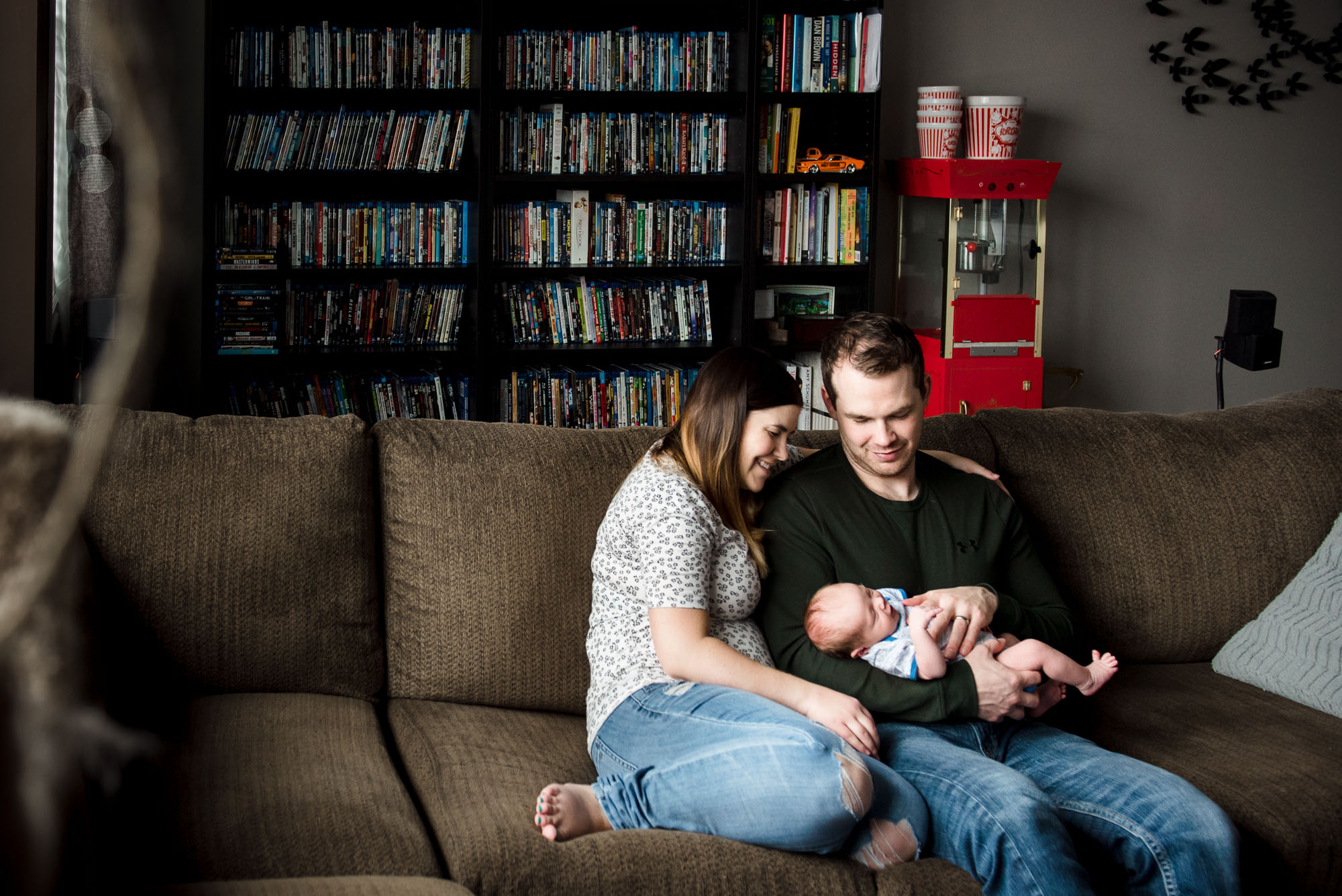 A family sits with their baby in their movie room. By Edmonton Newborn Photographer, Fiddle Leaf Photography