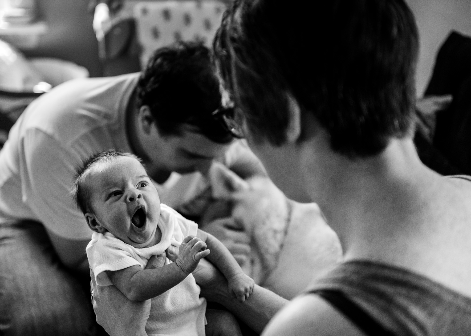 A newborn baby girl yawns in her newborn photo session