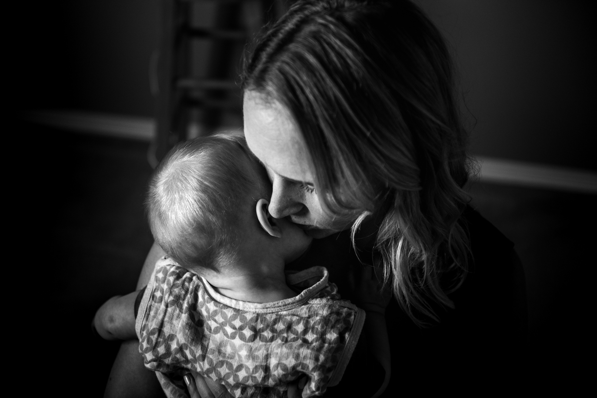 A mom snuggles her baby as part of a family photo session by Fiddle leaf Photography