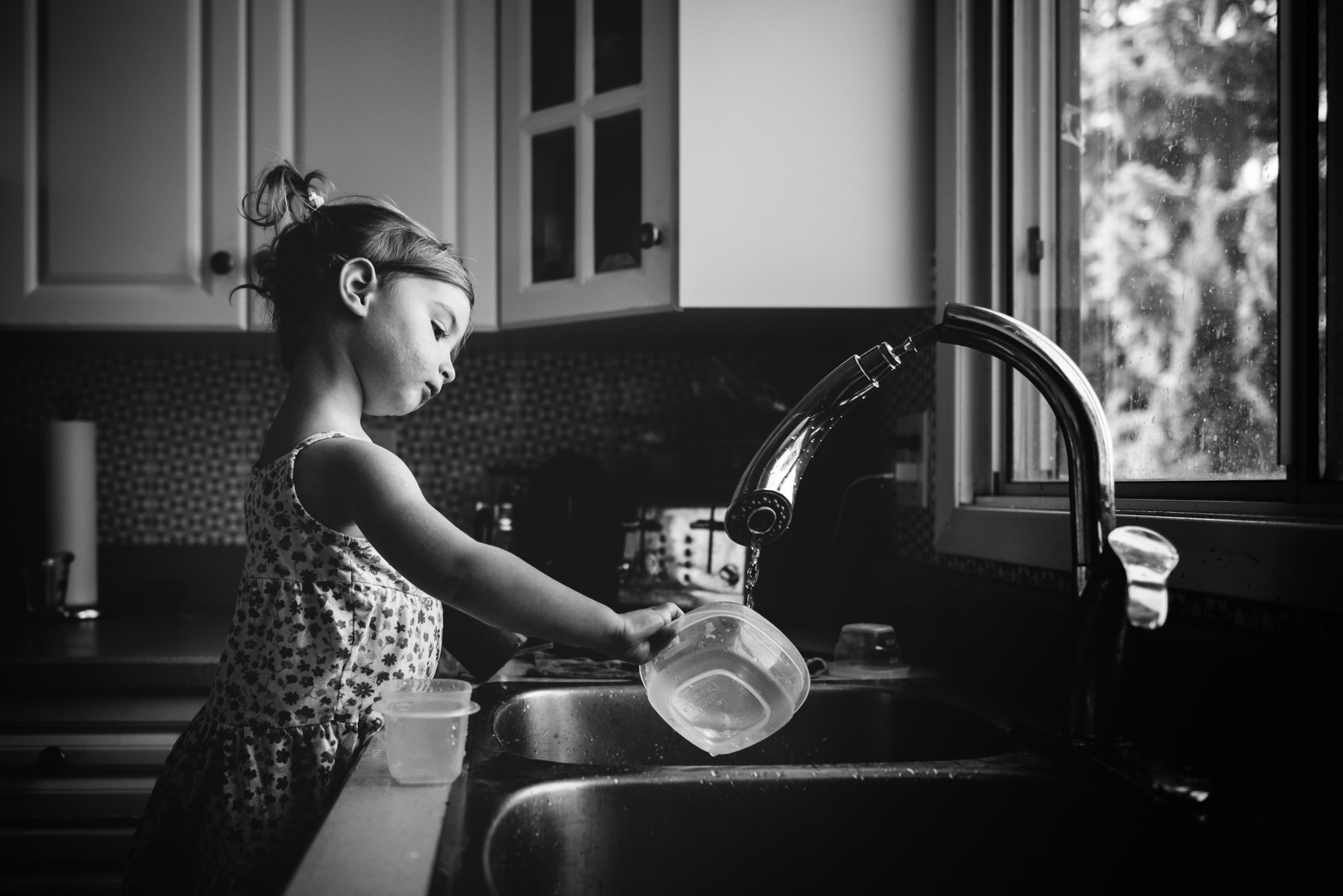 A little girl plays in the sink