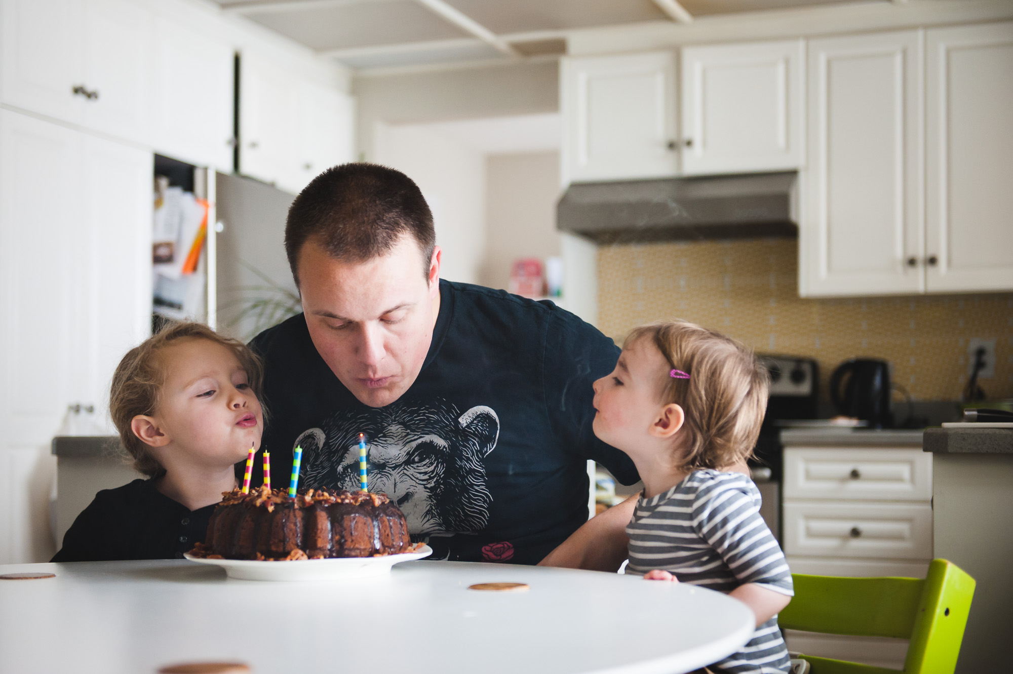 2 girls help their dad blow out candles