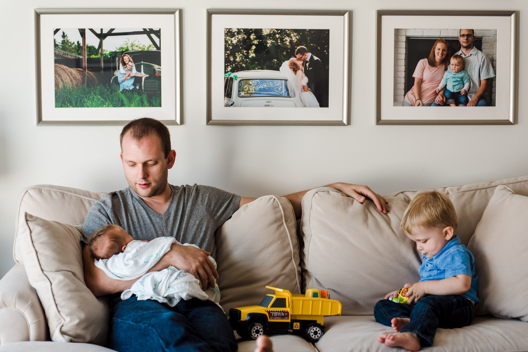 A dad sits in his sherwood park home with his toddler son and newborn baby daughter