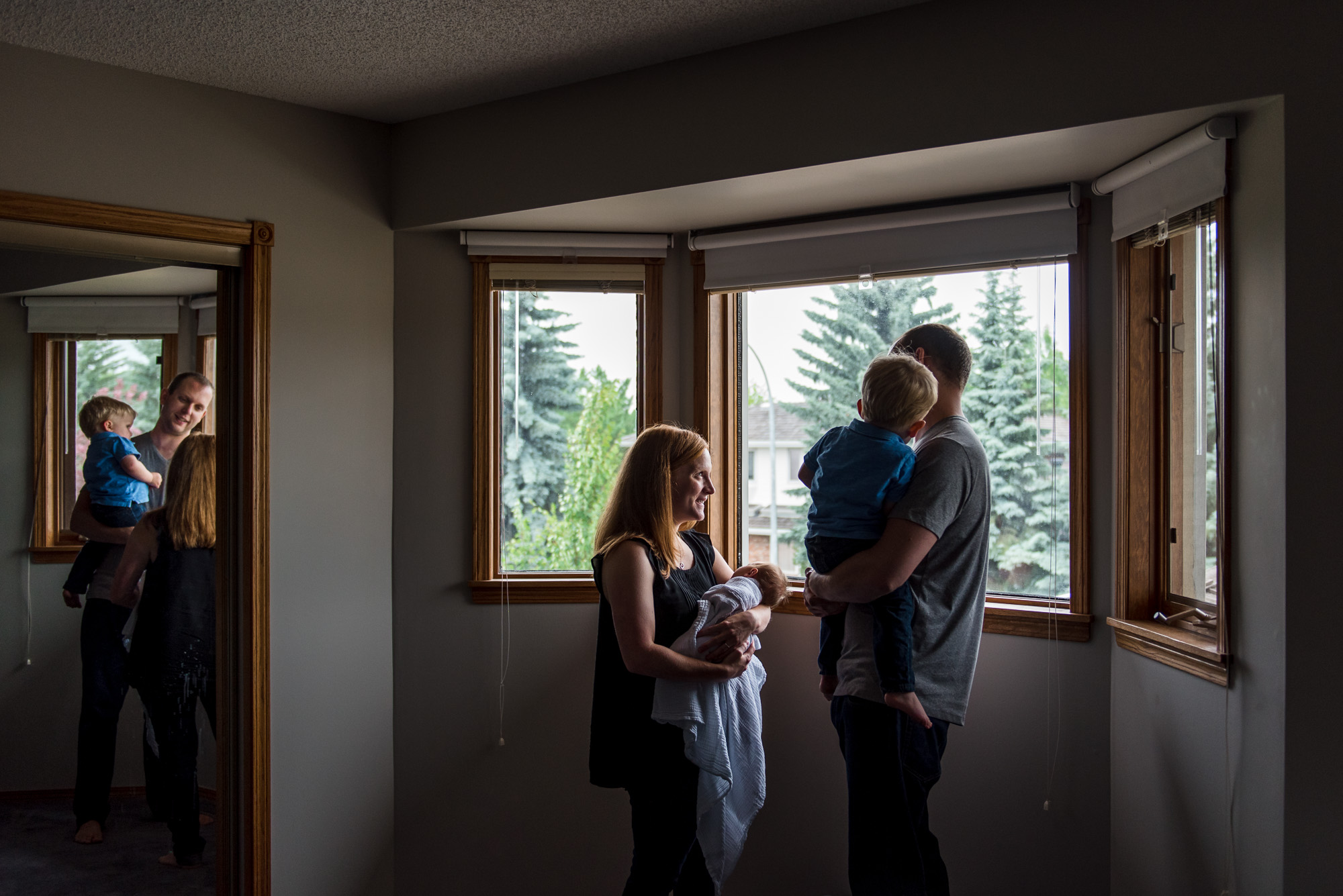 A family stands in their Edmonton home during a newborn photo session