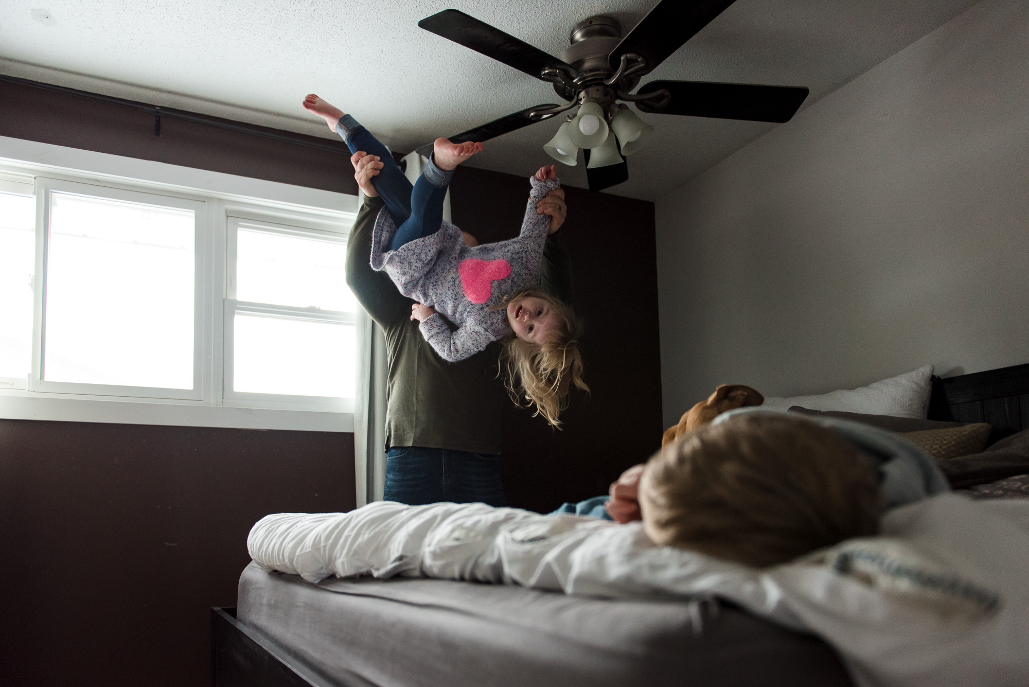 A dad tosses his daughter in the air during a sherwood park family photo session