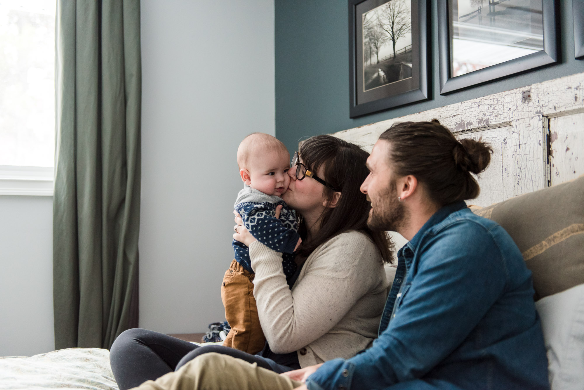 A mom kisses her baby son while dad looks on