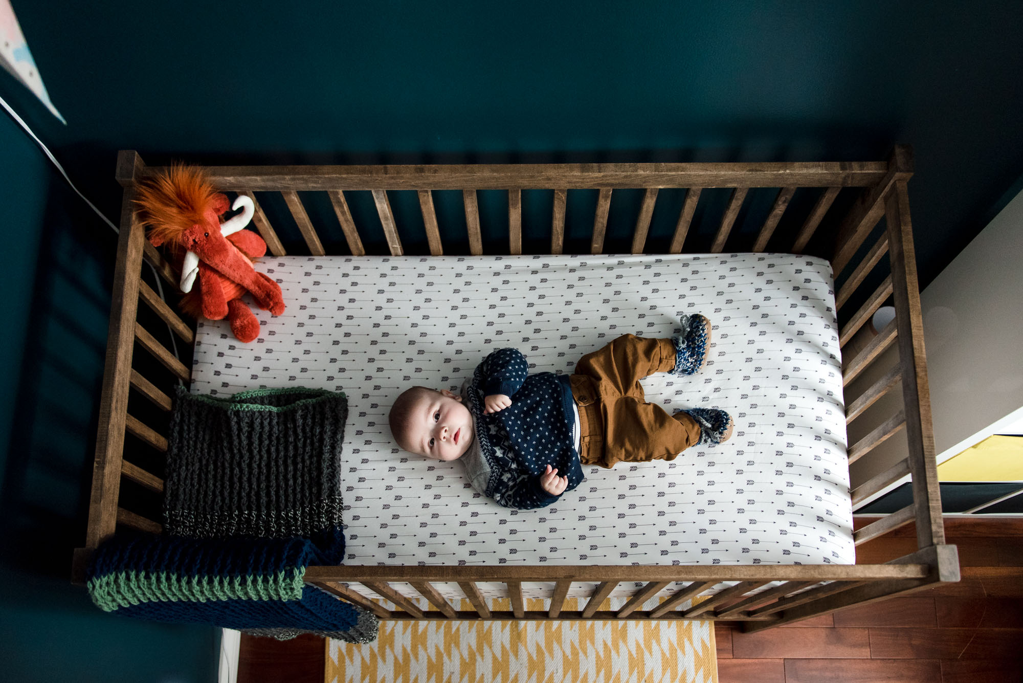 A baby boy lays in his crib during a Fort Saskatchewan family photo session