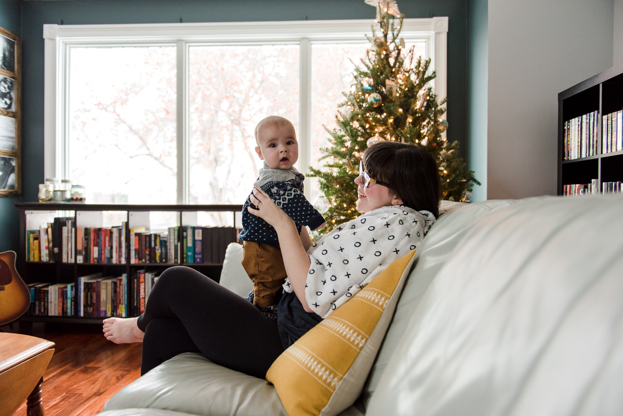 A mom and baby by a christmas tree in their Fort Sask home