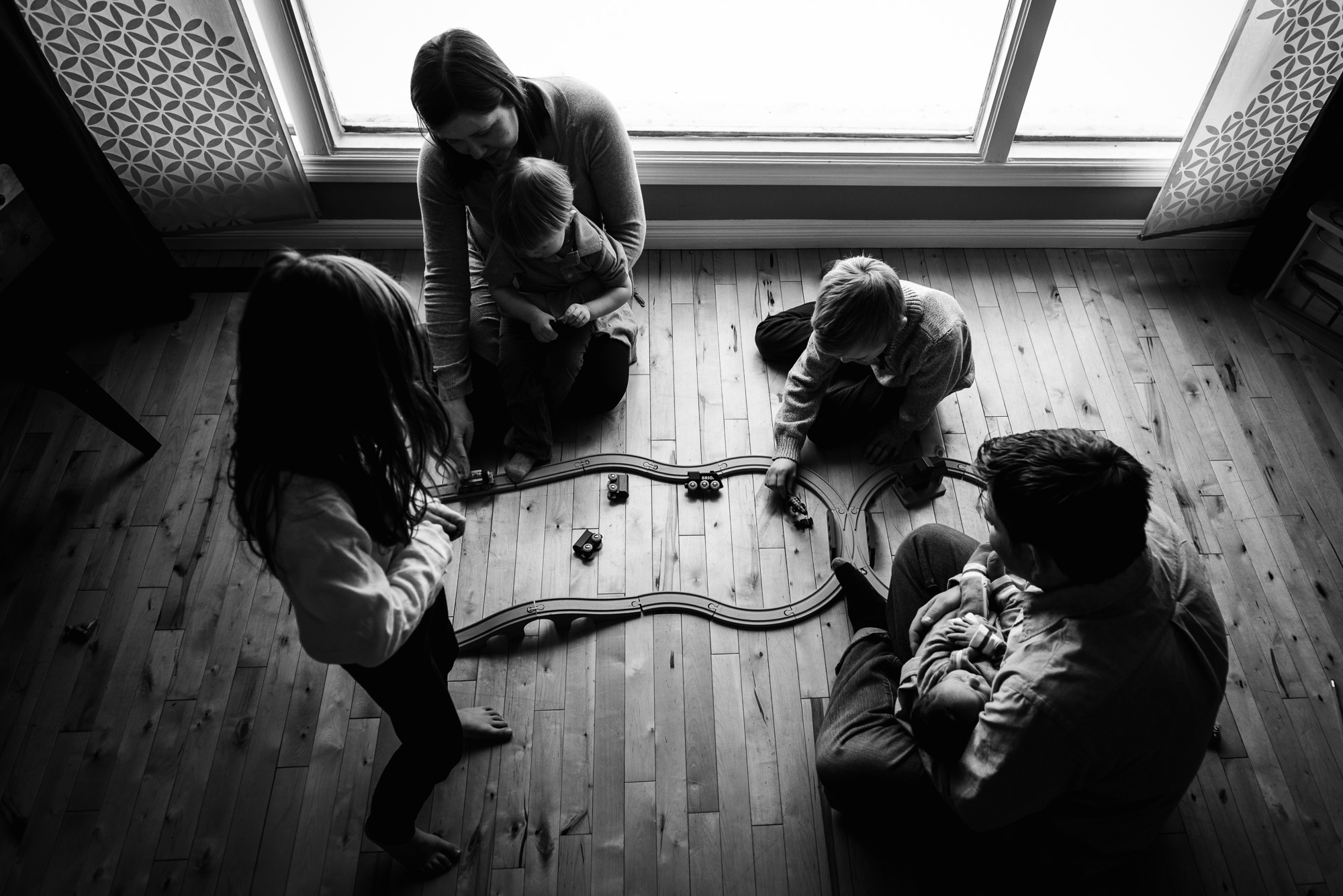 A family plays trains during their lifestyle newborn photo session in their Edmonton home. 