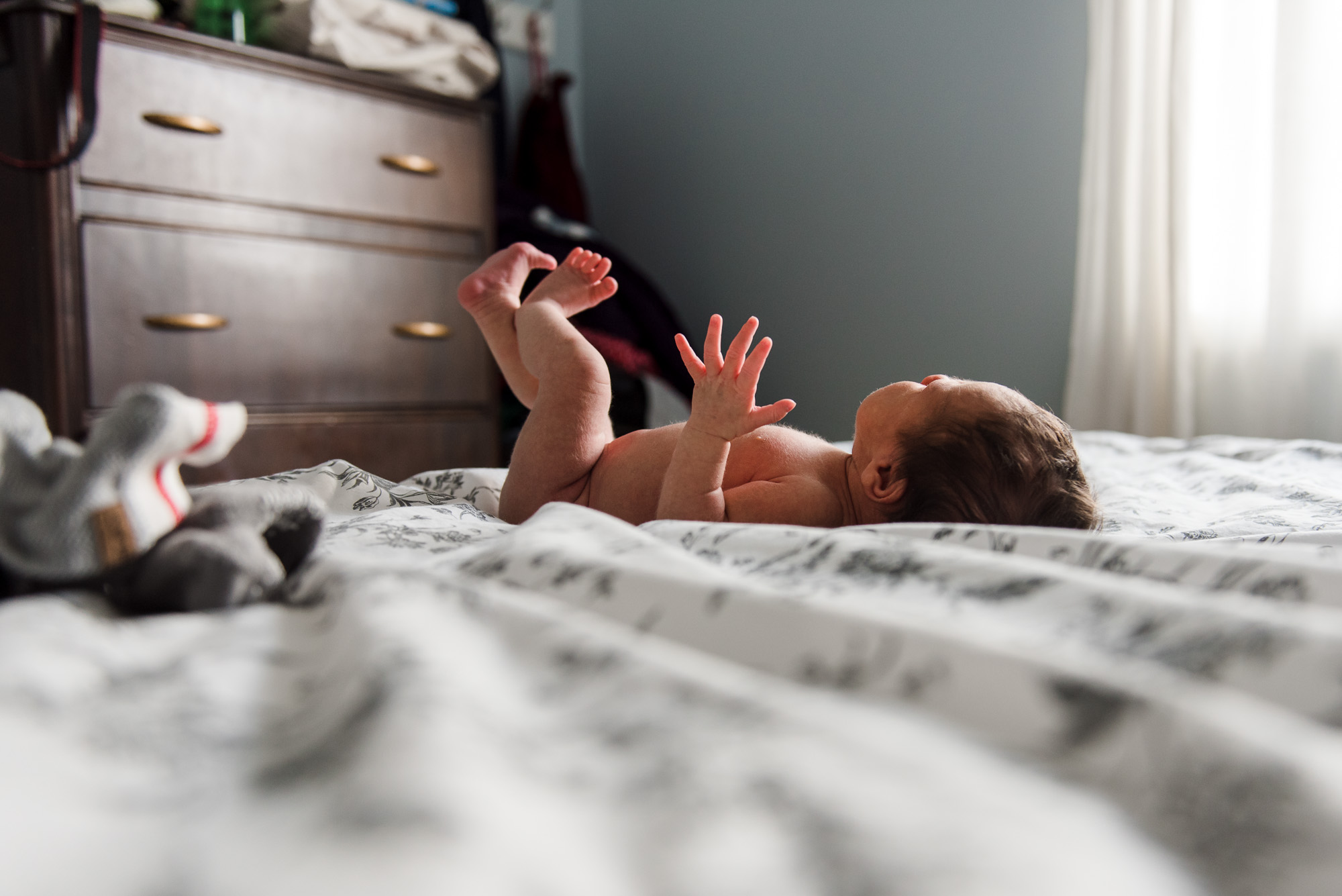 A newborn baby lays on a bed in the light