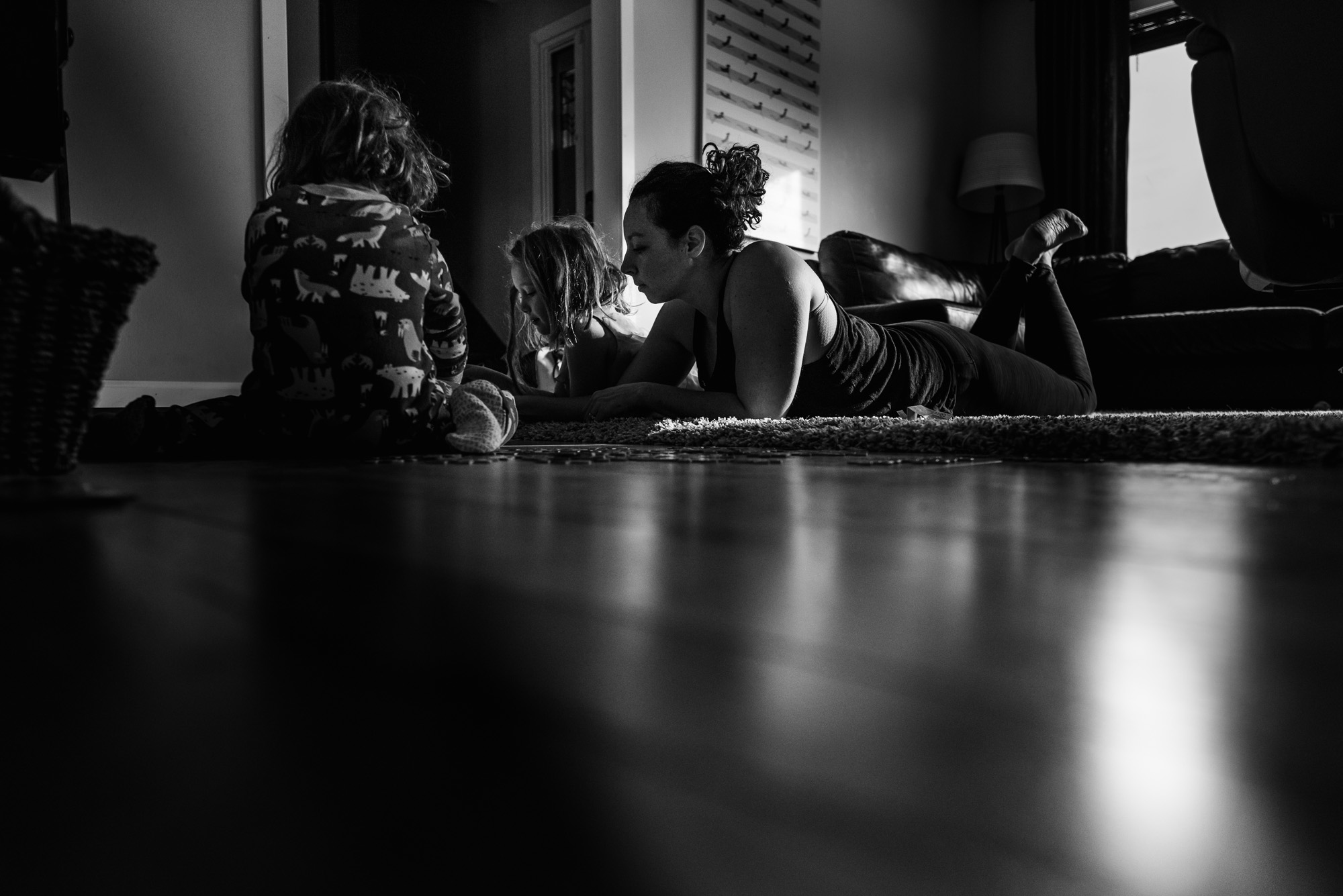 A mom plays puzzles with her daughters on their Edmonton living room floor 