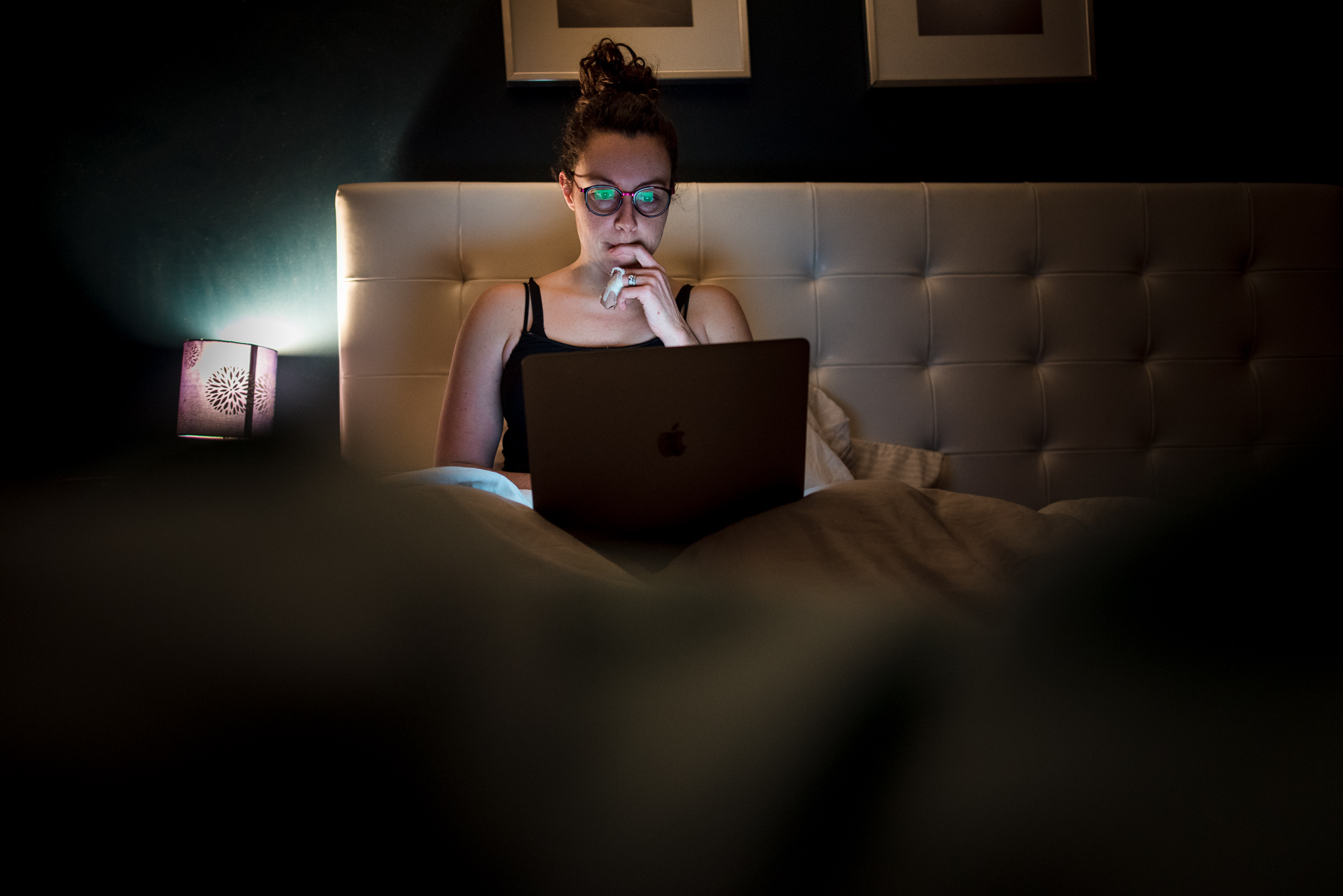 A mom works in her bed using her laptop. low light self portrait