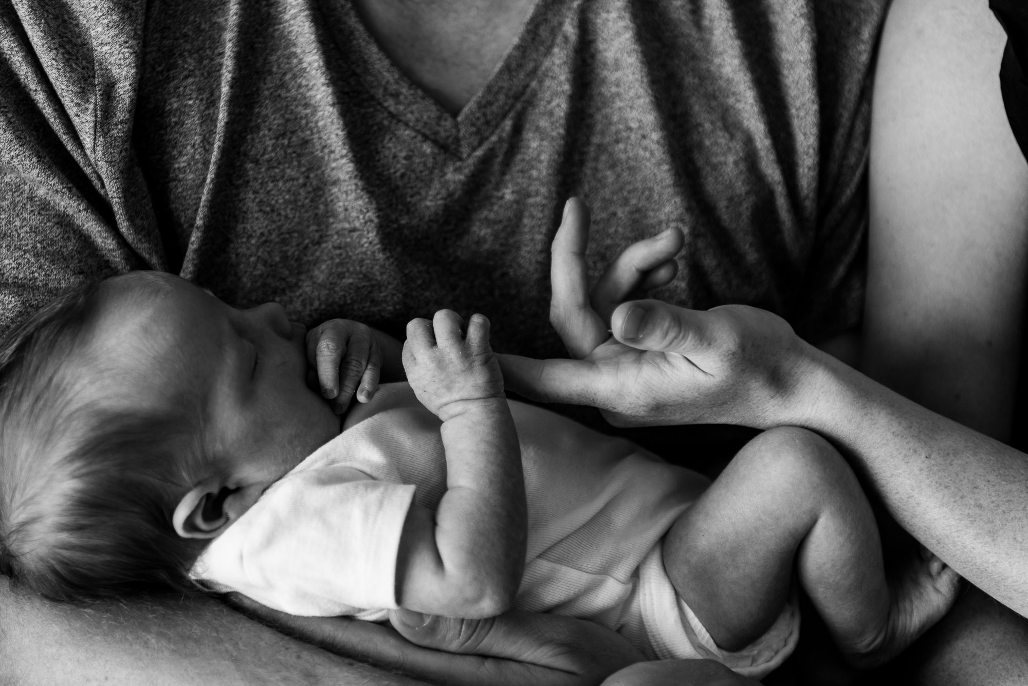 A mother holds her baby's hand during a newborn photo session