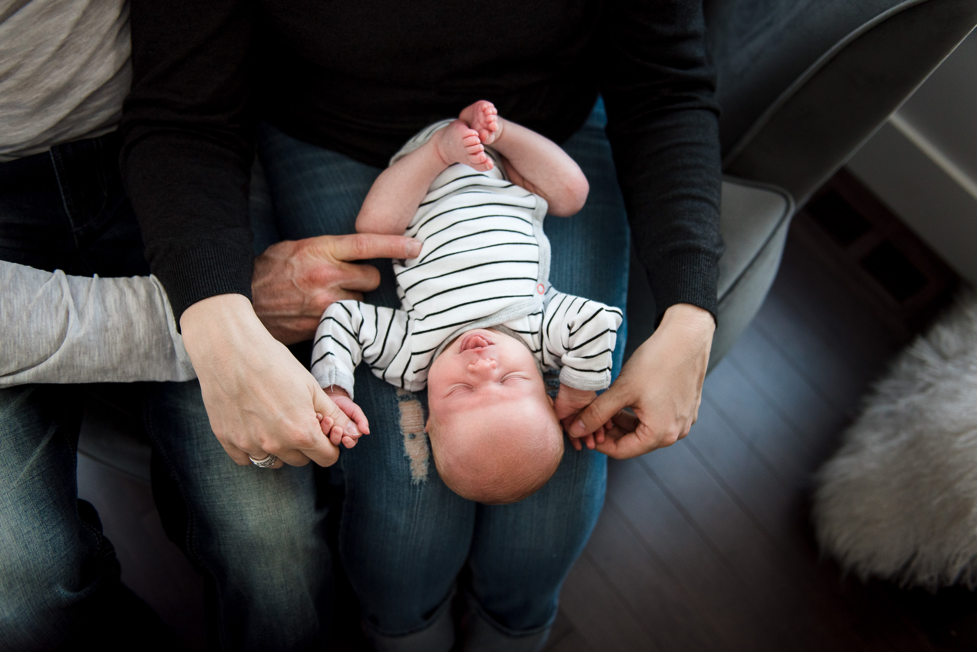 Parents touch their newborn baby during an Edmonton newborn photo session
