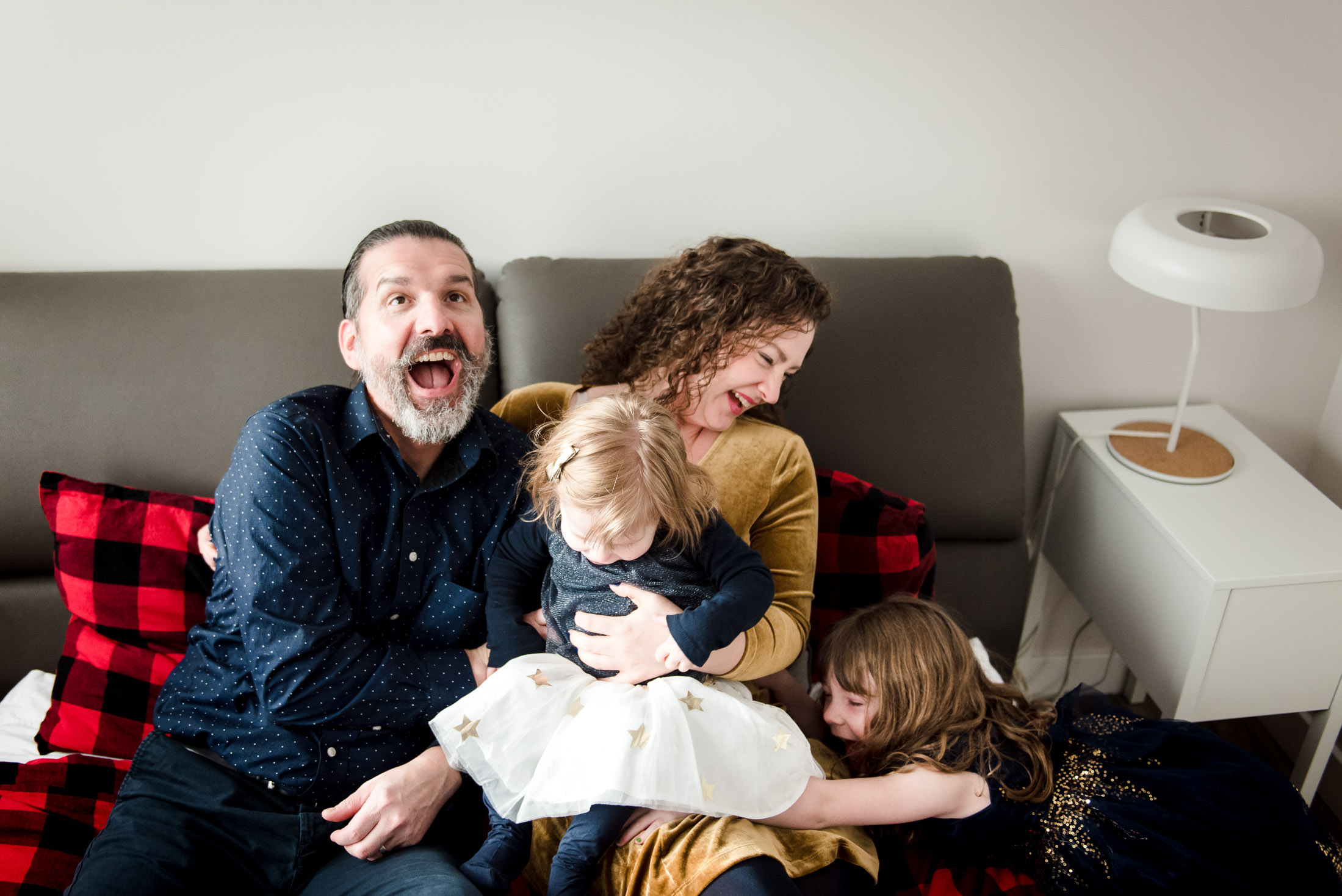 A family laughs while snuggled on the bed during holiday short session by Fiddle Leaf Photogrpahy
