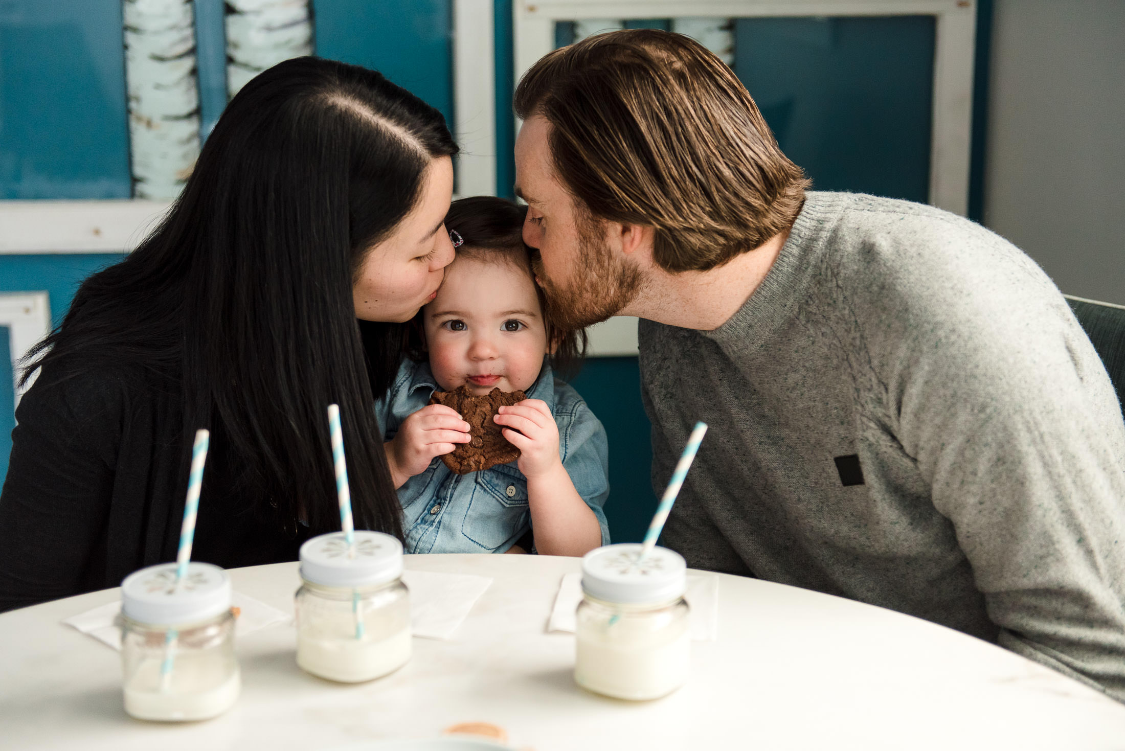 Parents kiss their daughter during family photos by Fiddle Leaf Photography 