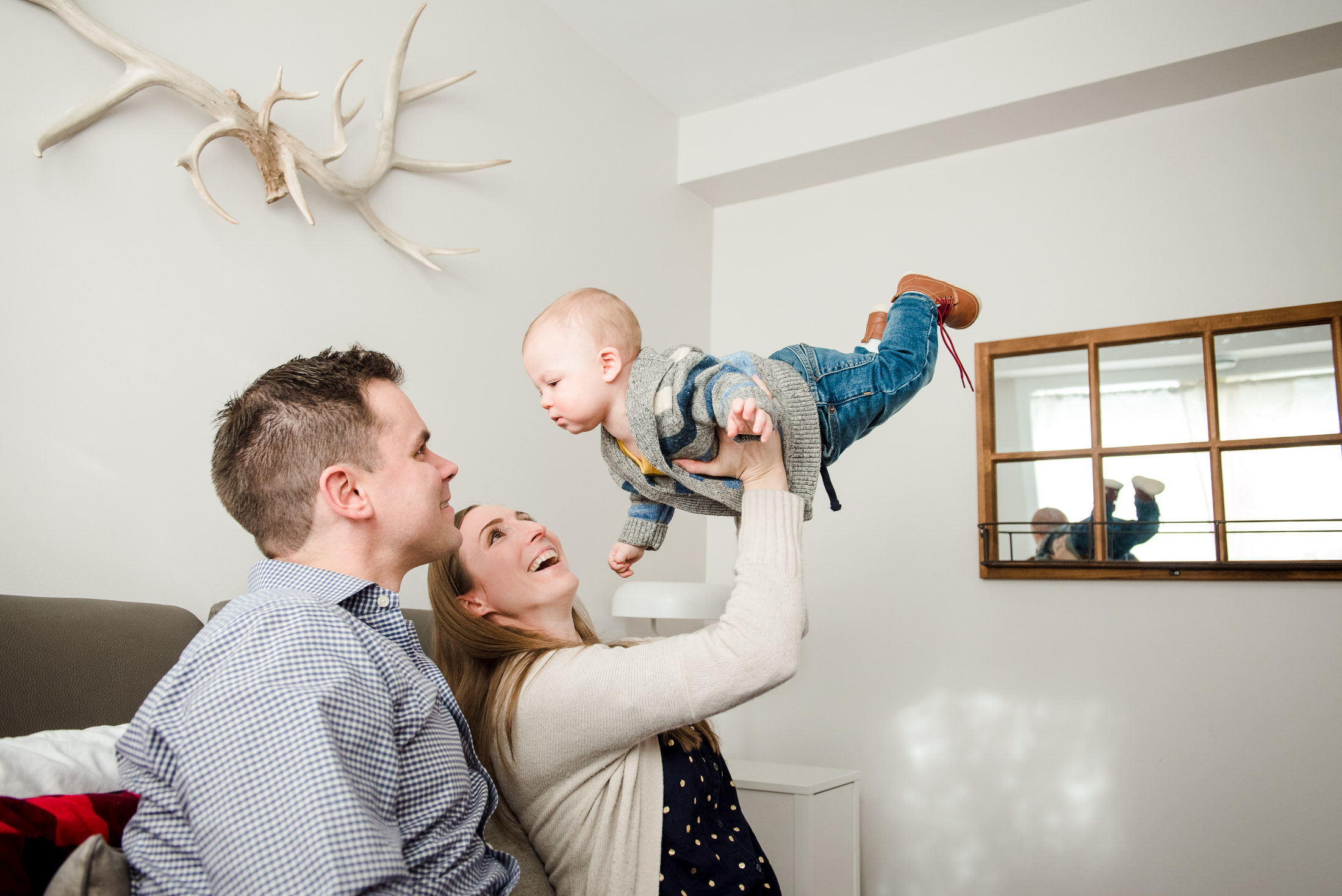 A mom lifts her little boy in the air during family photos in an Edmonton studio