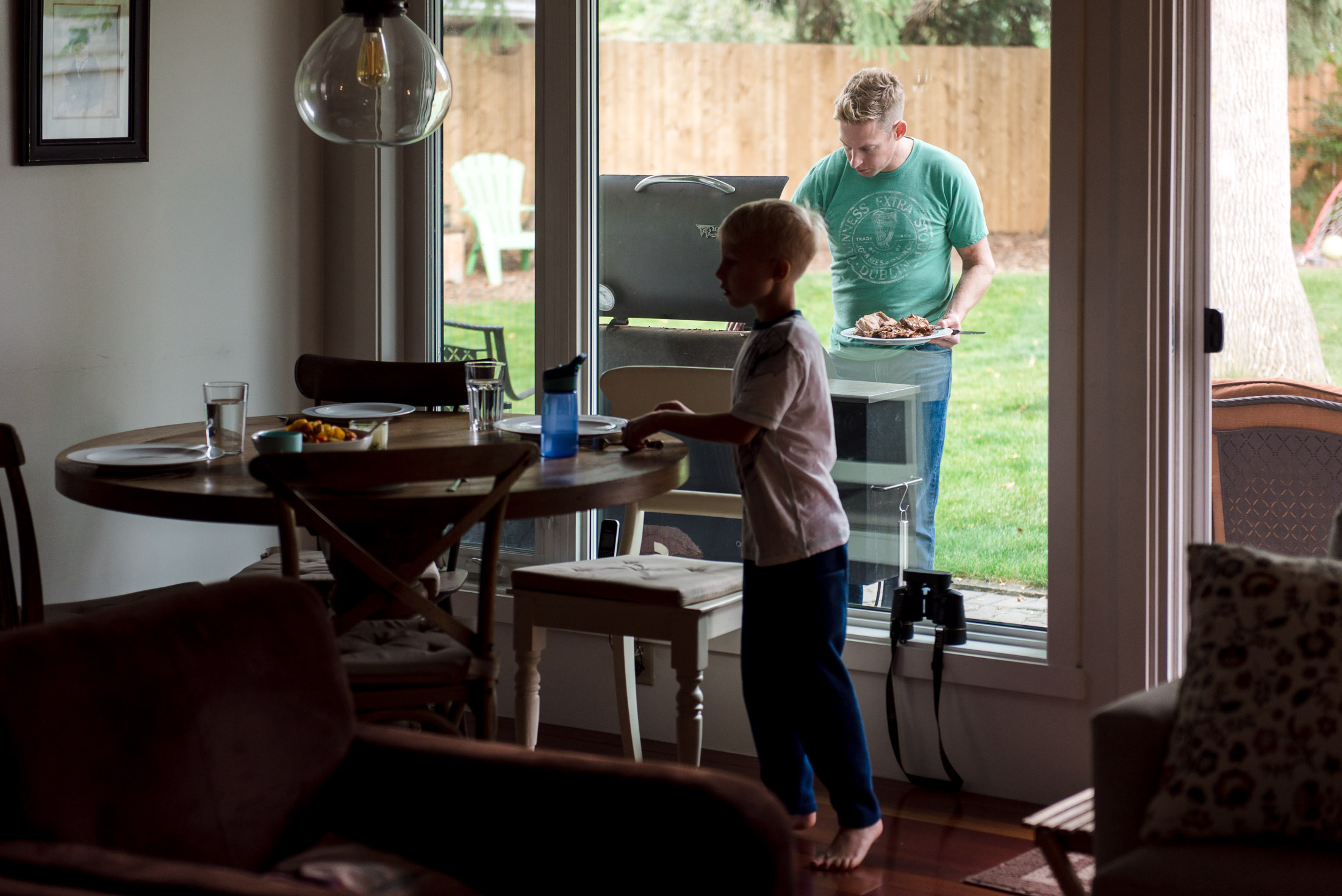 A dad makes dinner while a boy sets the table in their Edmonton home.