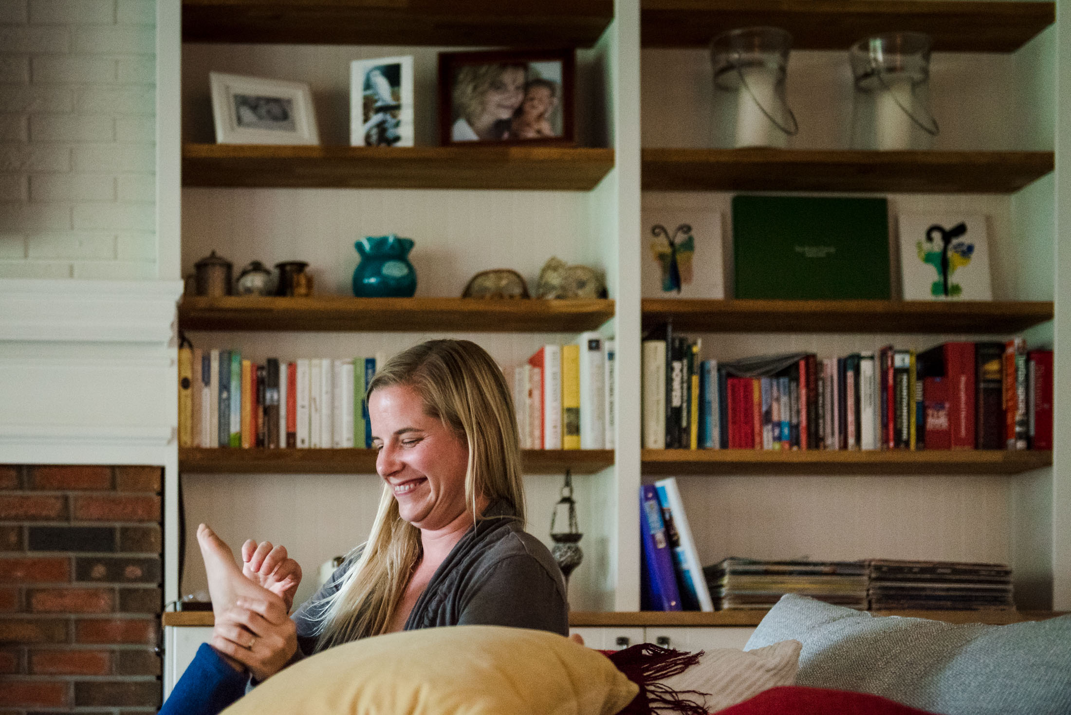 A mom tickles her daughter's foot during family photos day in the life.