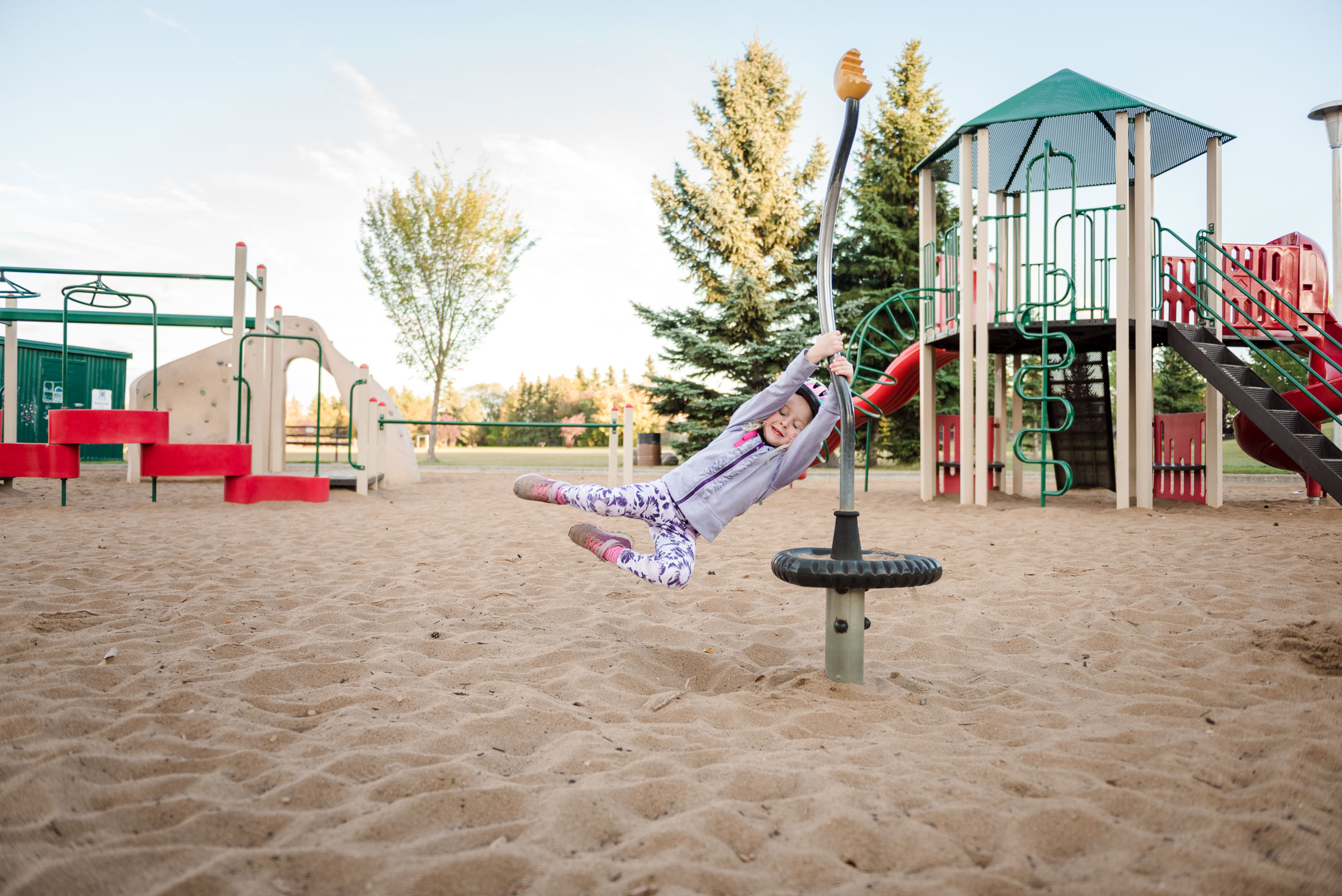 A little girl spins at an Edmonton playground during a fun family photo session