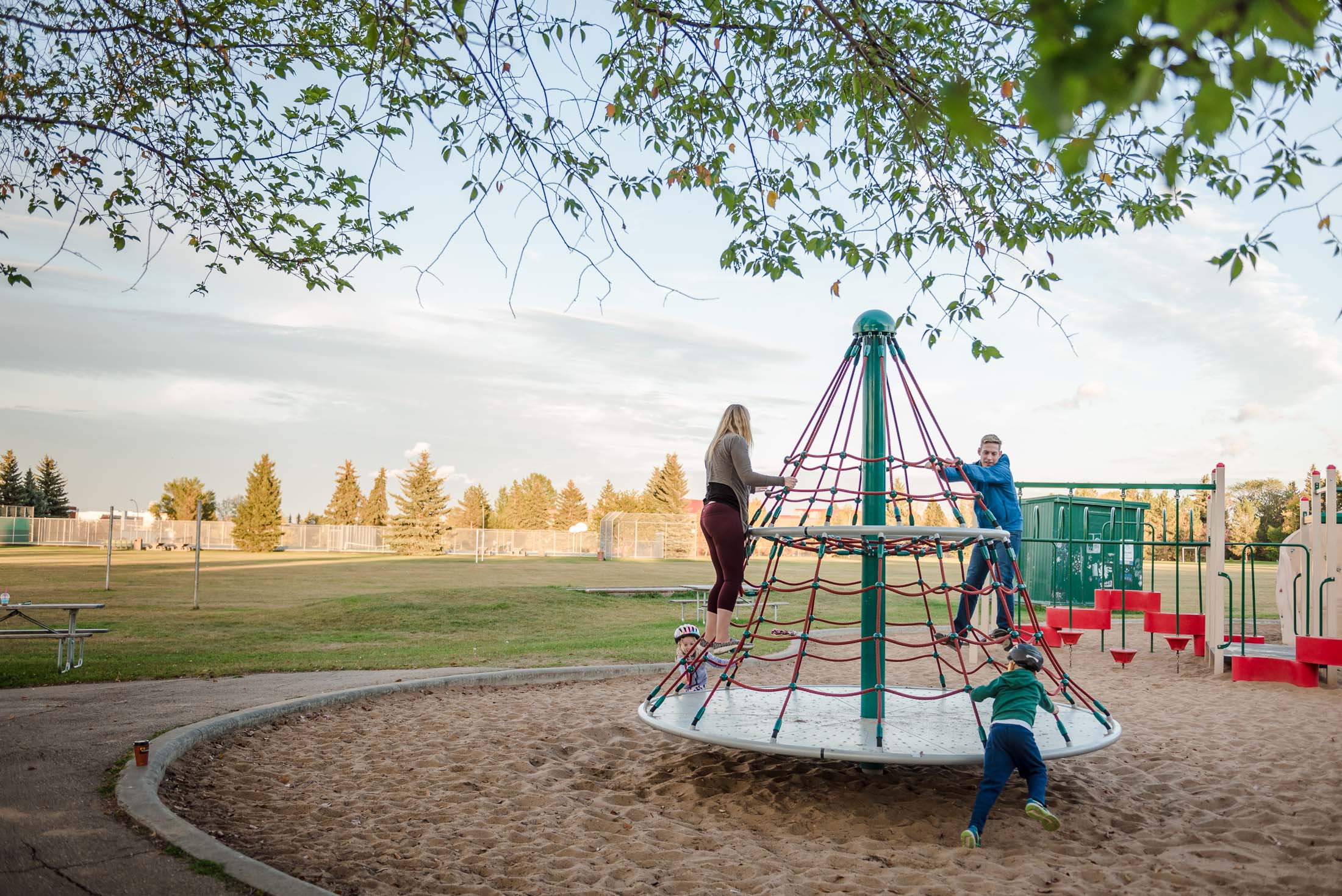 A family plays at an Edmonton playground as part of their family photo session