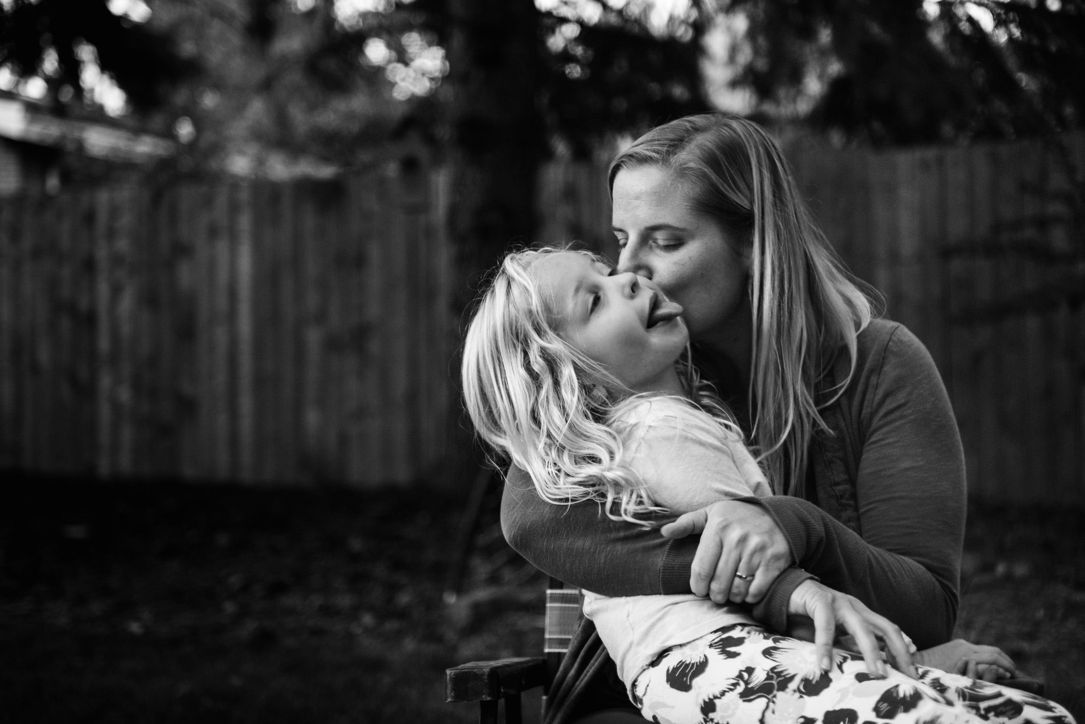 A mom kisses her daughter in their edmonton backyard