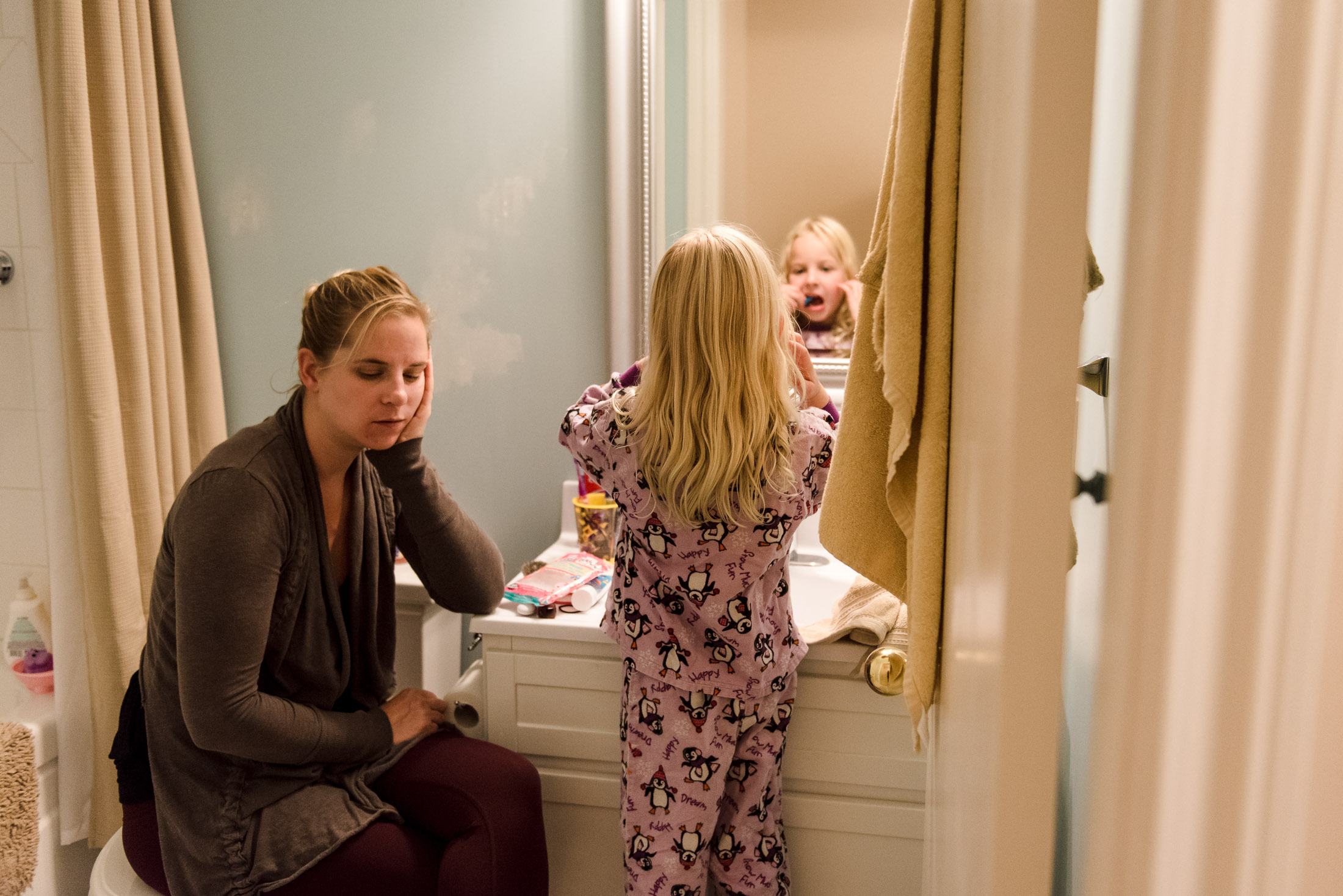 A mom waits for her daughter to brush her teeth as part of a day in the life photo session