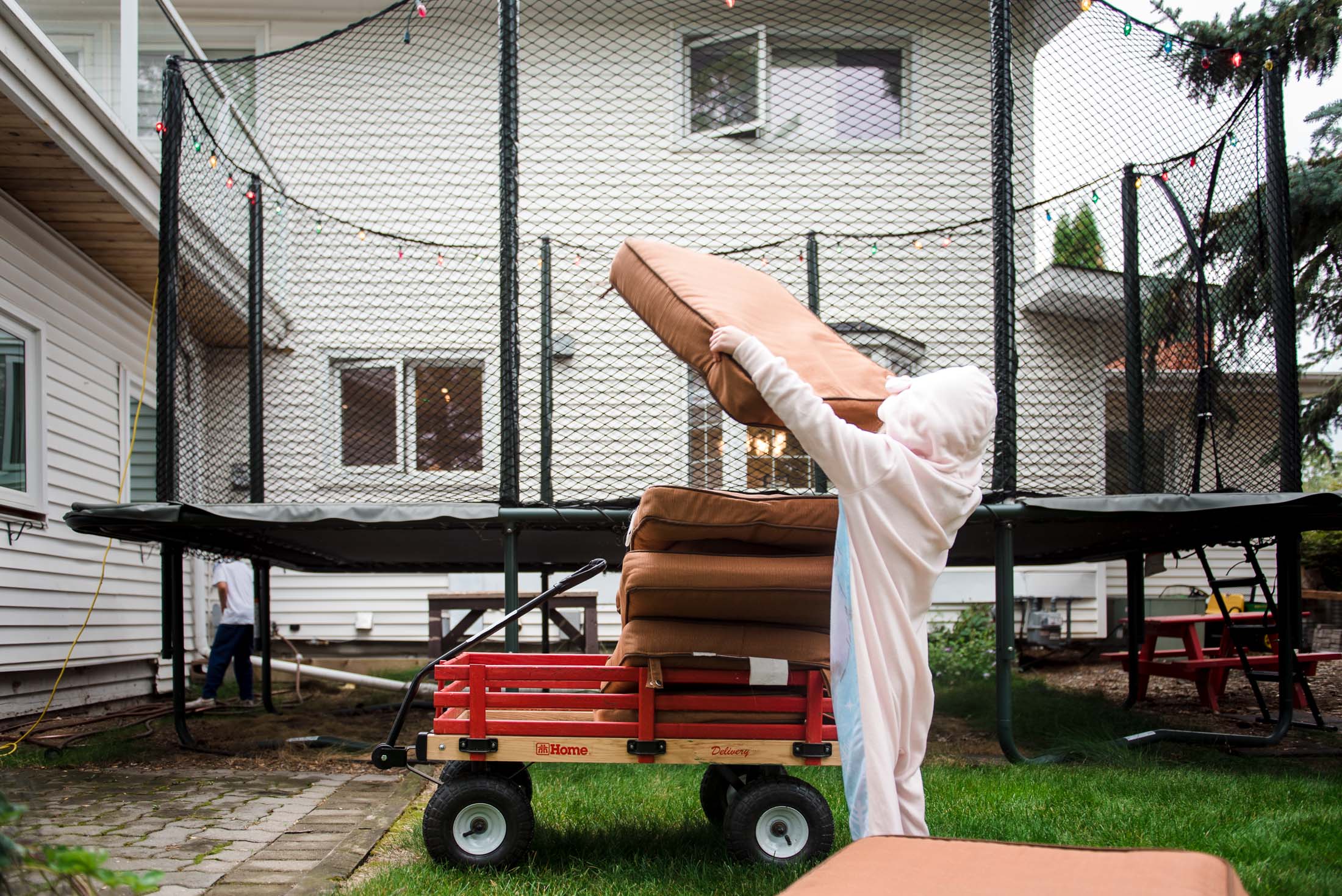 A girl stacks up cushions in her Edmonton backyard during a documentary family photo session