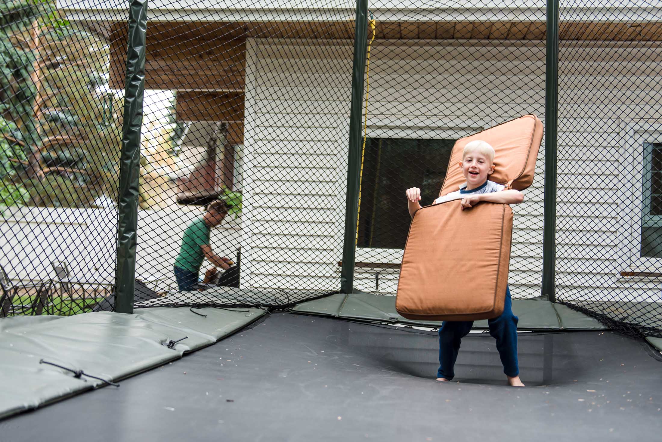 A boy goofs around on a trampoline during family photos by Fiddle Leaf Photography