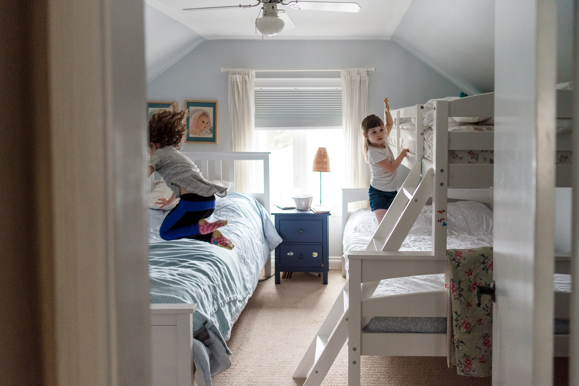 Kids jump on their beds as part of their documentary family photo session