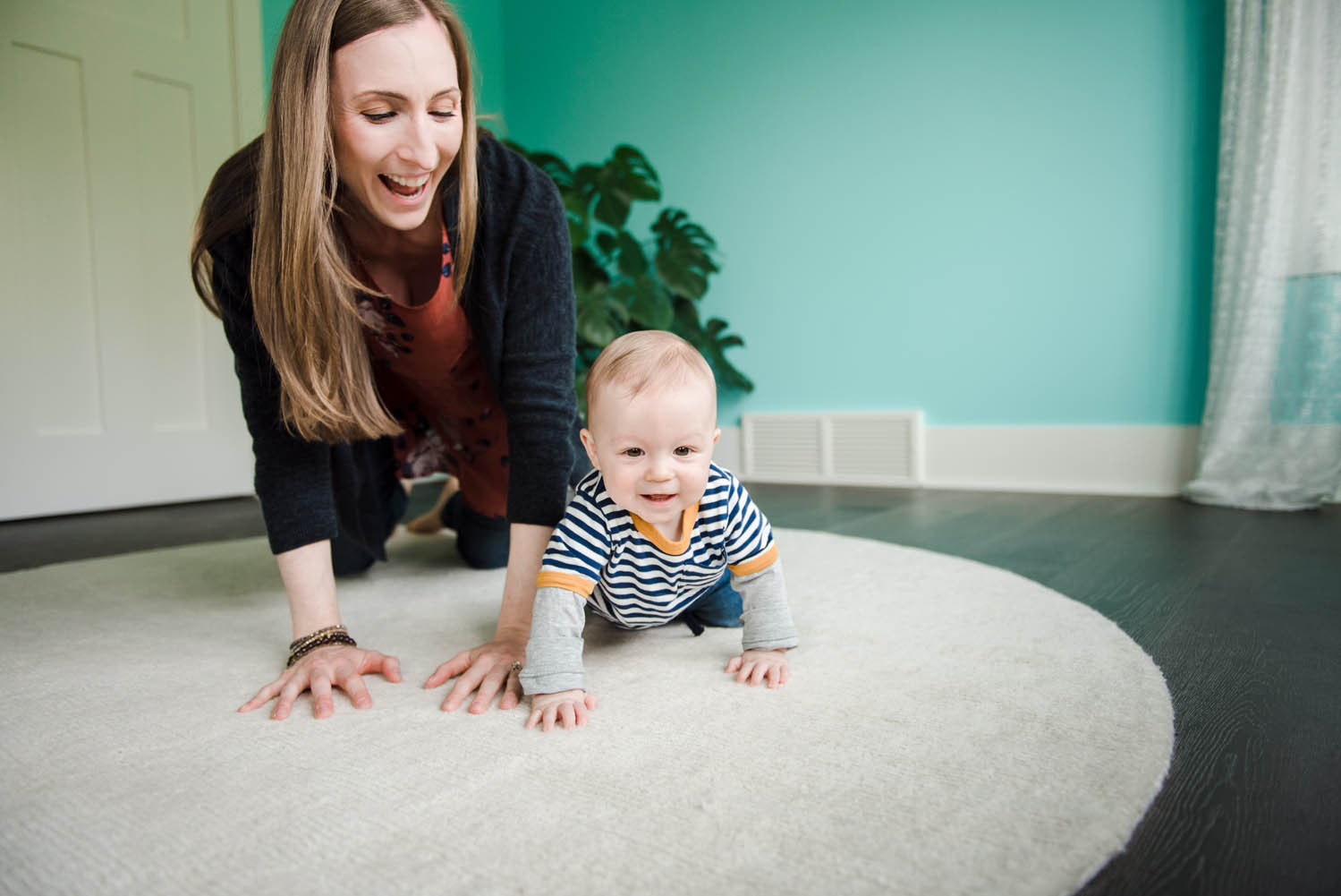 A mom crawls with her 8  month old baby during an in home family photo session. 