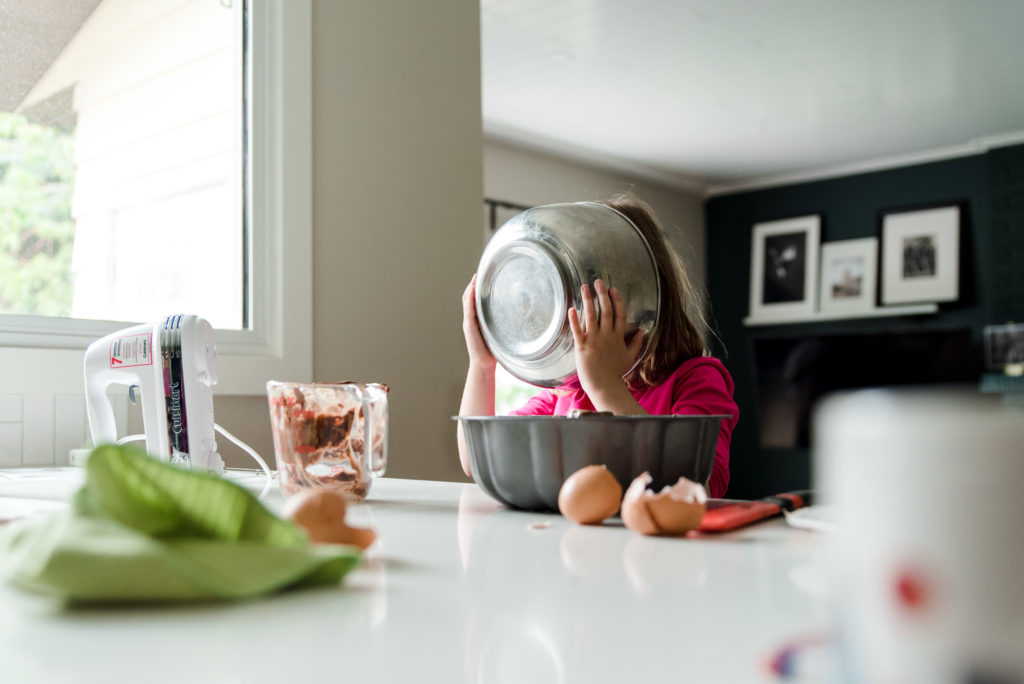 A little girl licks a baking bowl