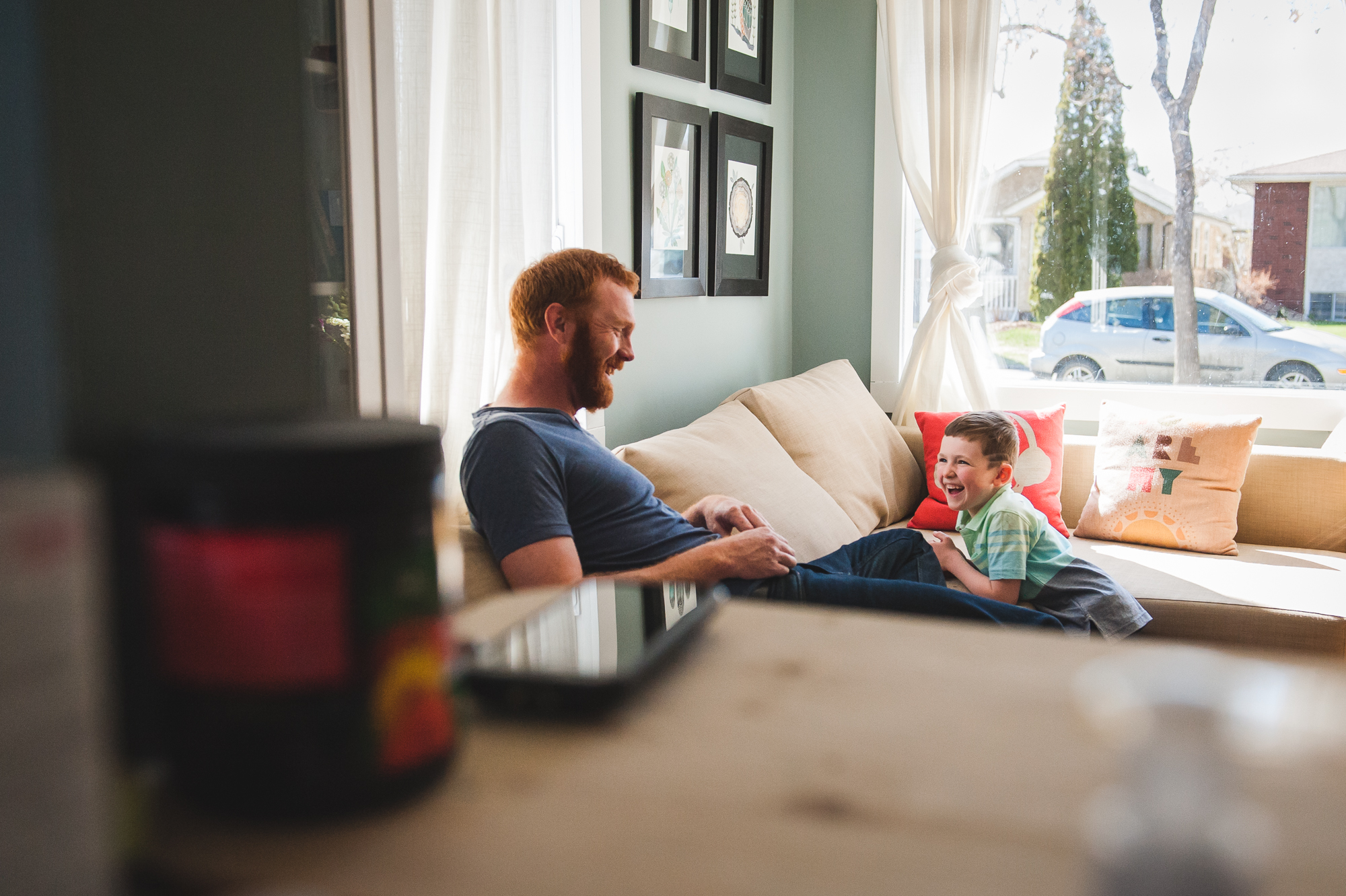Father and Son sitting in living room. Best Family Photographer Edmonton. In-home family photographer.