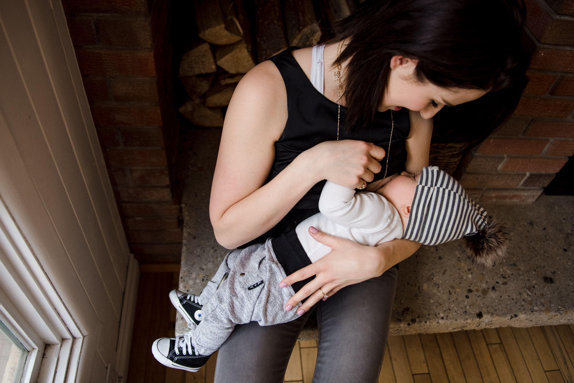 A woman breastfeeds her baby at Little Brick Cafe in Edmonton, Alberta wearing clothing from Yo Mama Maternity