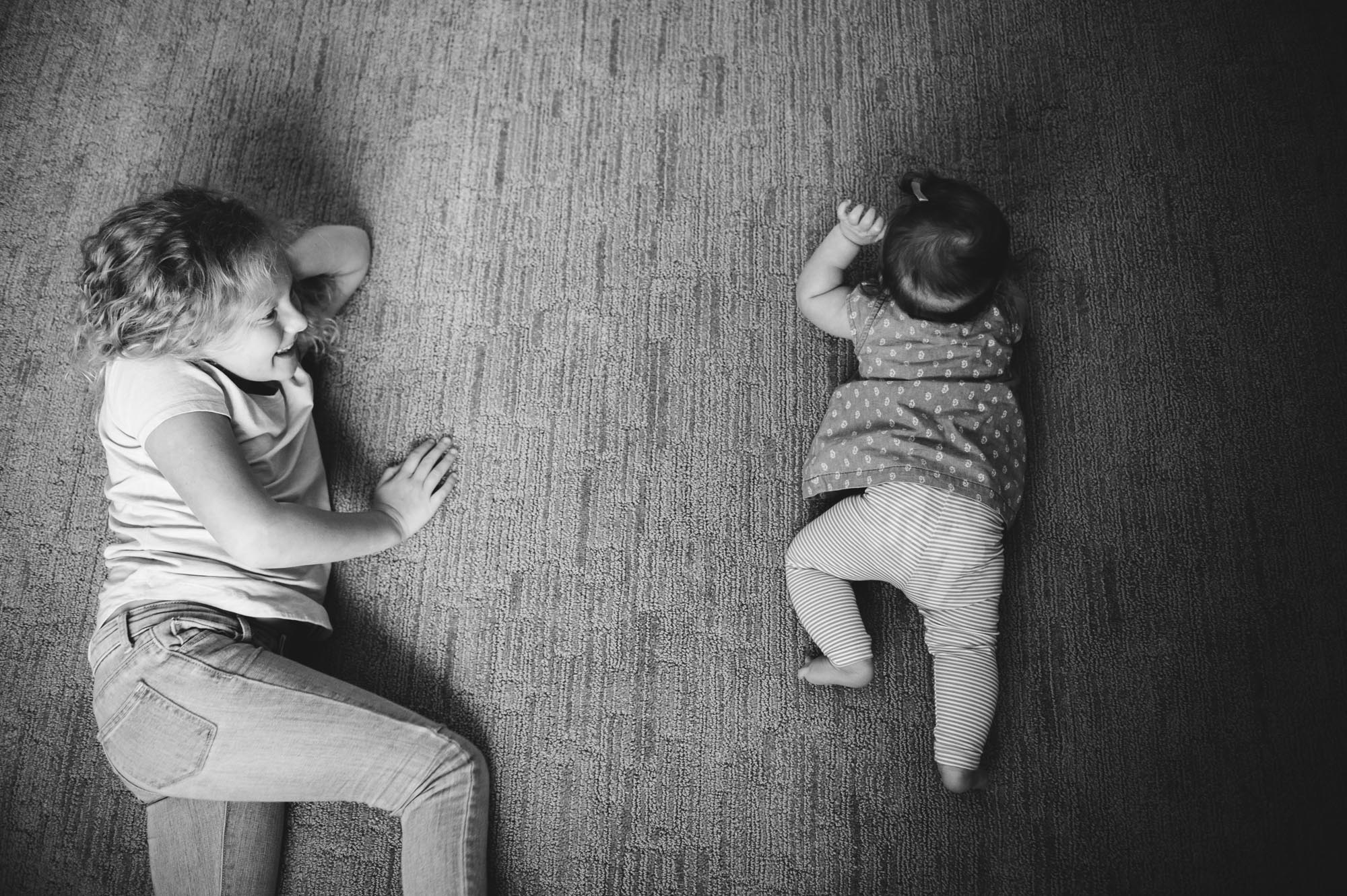 A baby practices crawling with her sister during a photo session