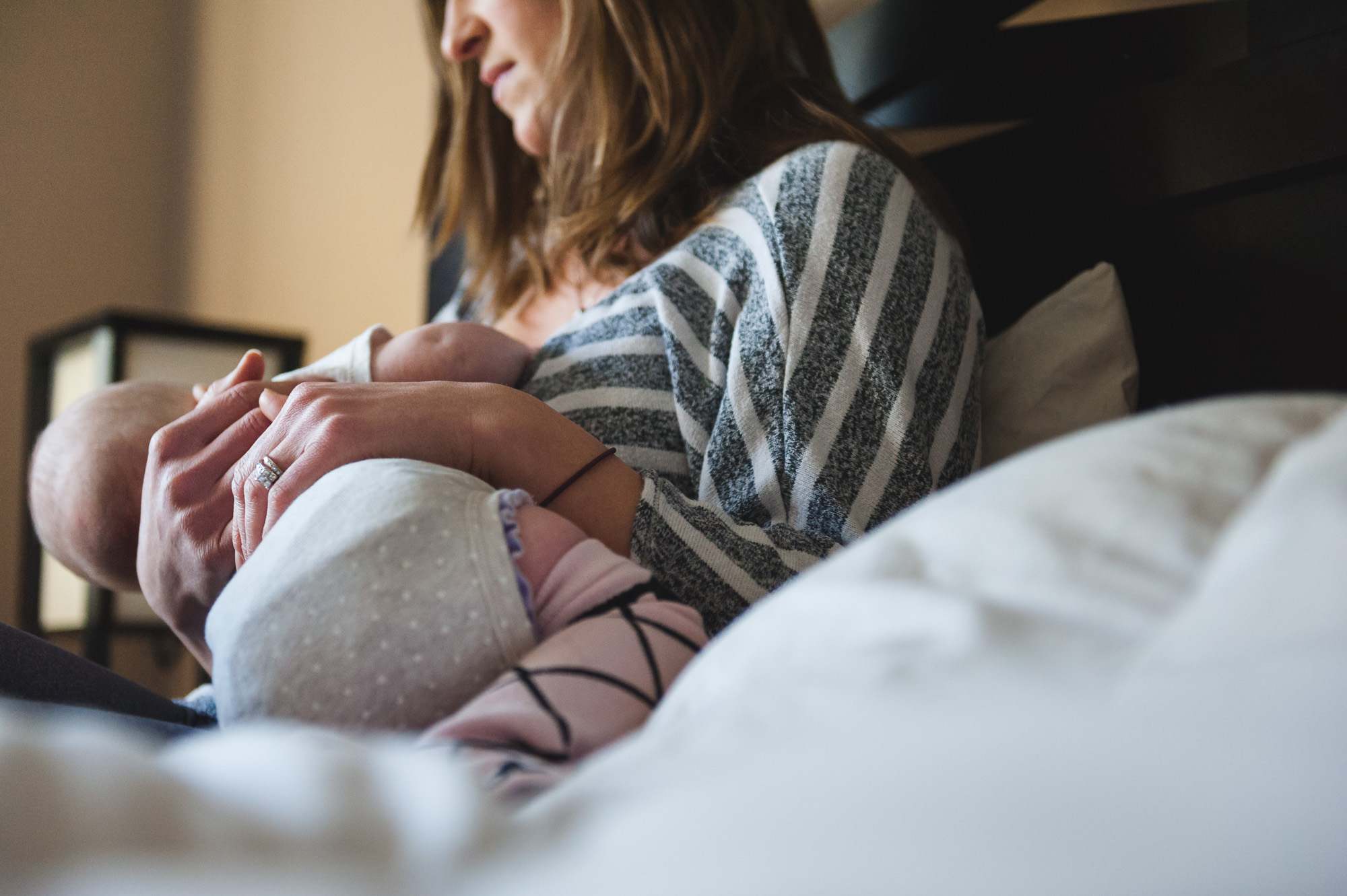 A mother breastfeeds her baby on a bed