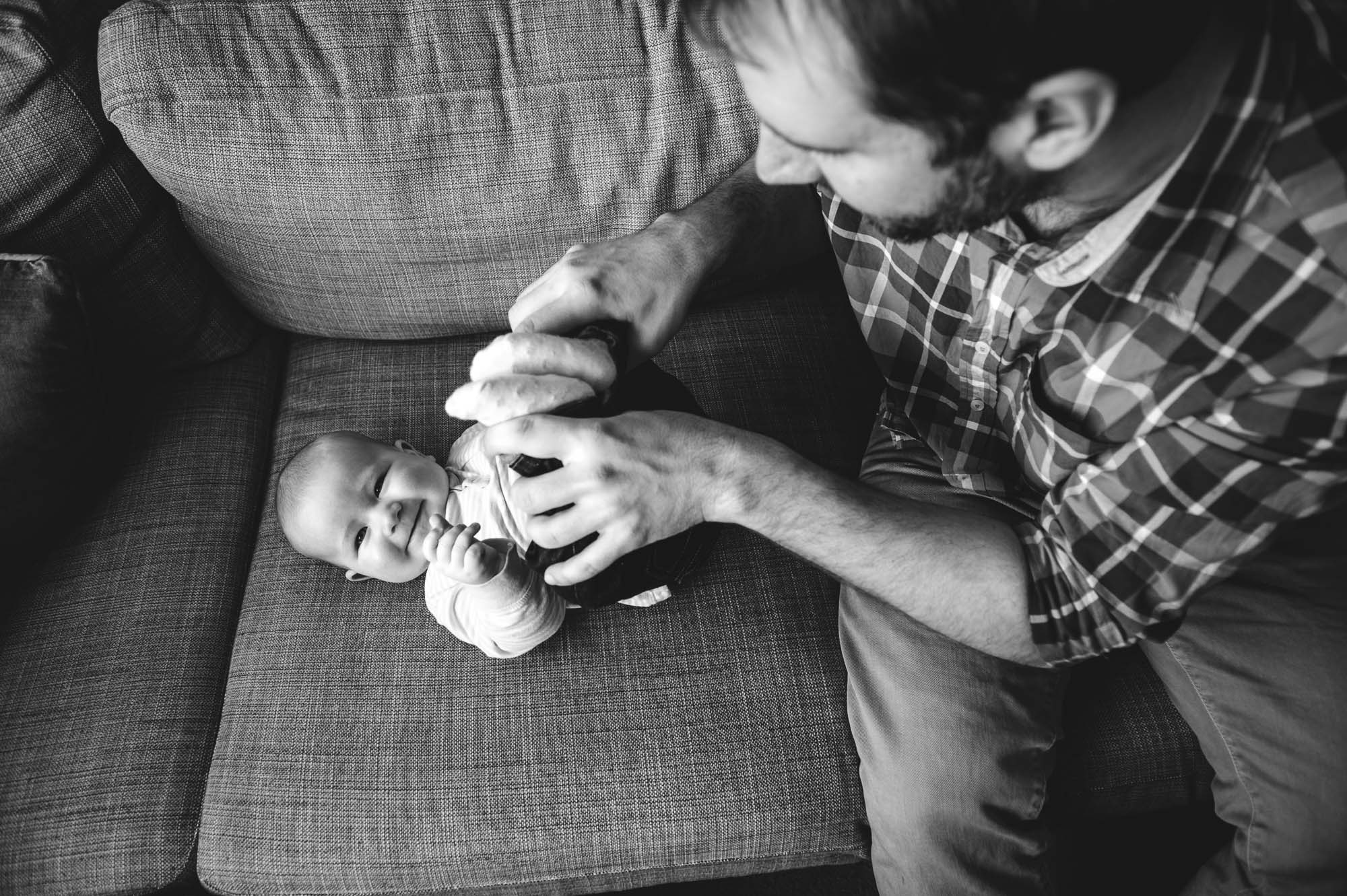 A dad tickles his baby on an Ikea couch 