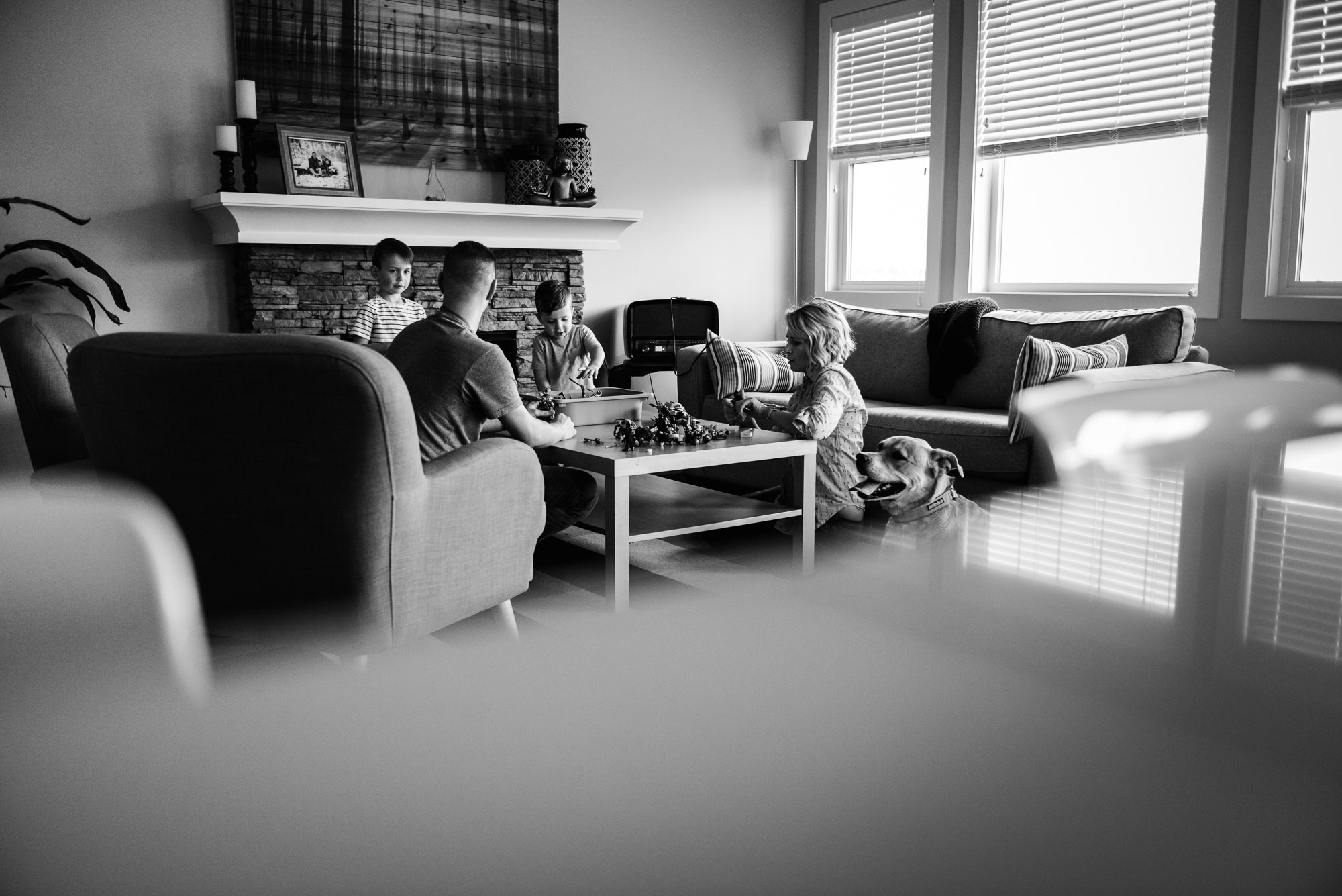 A family sits in their living room and plays action figures