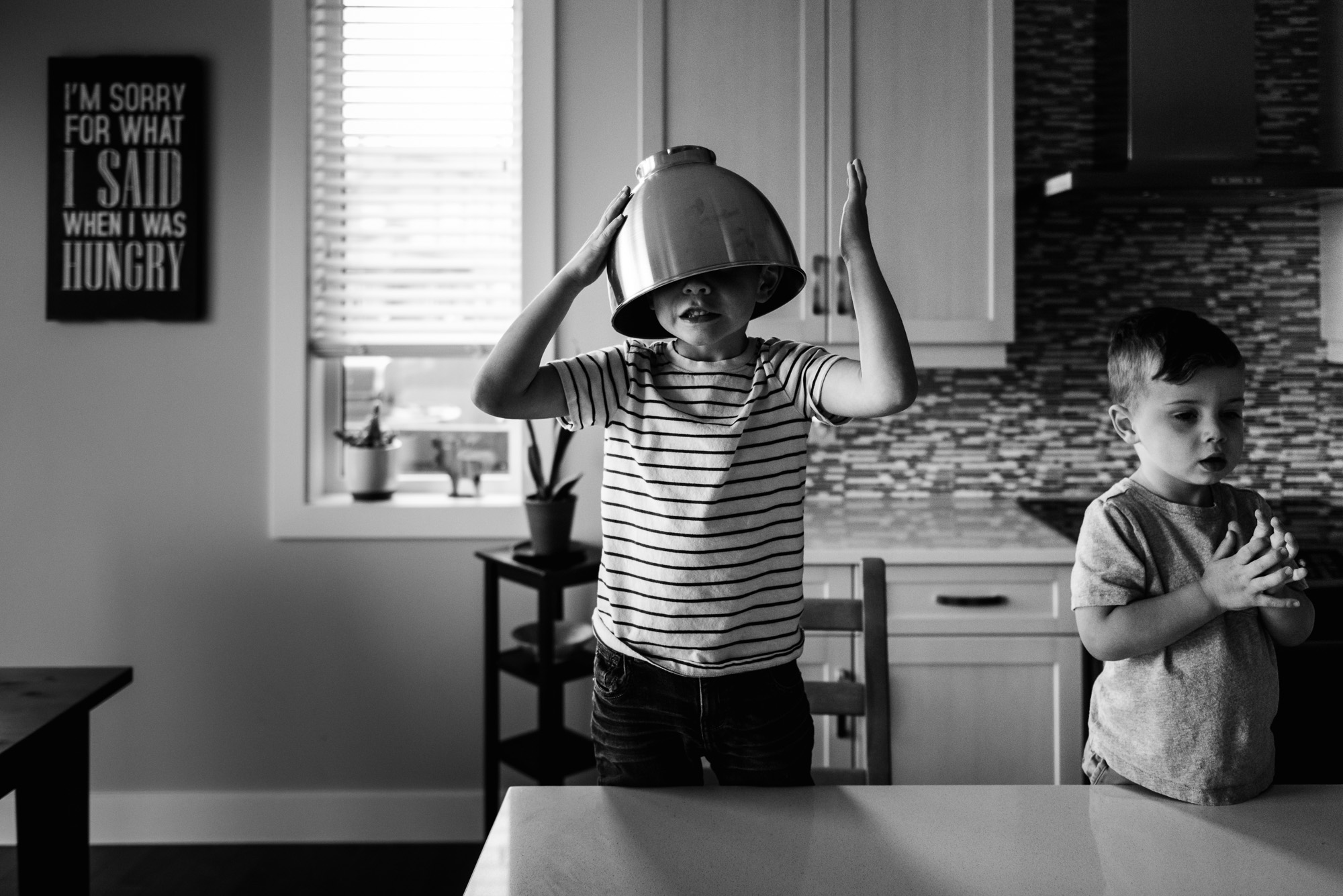 A boy puts a bowl on his head. 