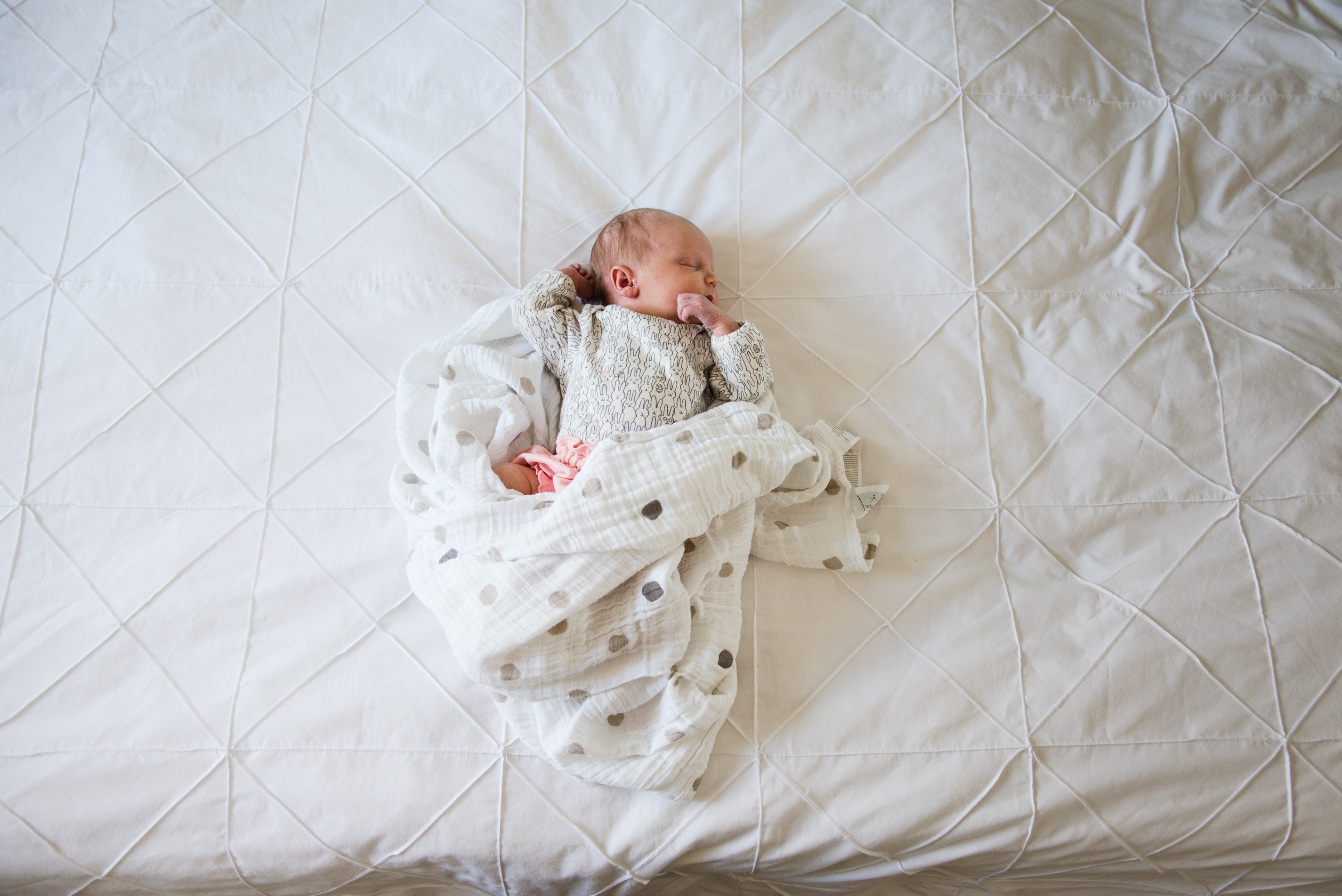 A newborn baby sleeping soundly on a bed.