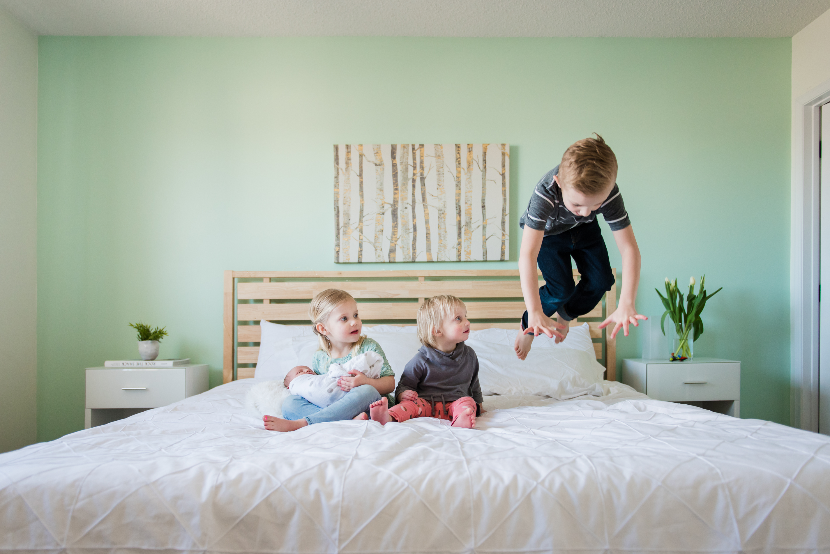 a little boy jumps on a bed during a newborn photo session in Sherwood Park Alberta