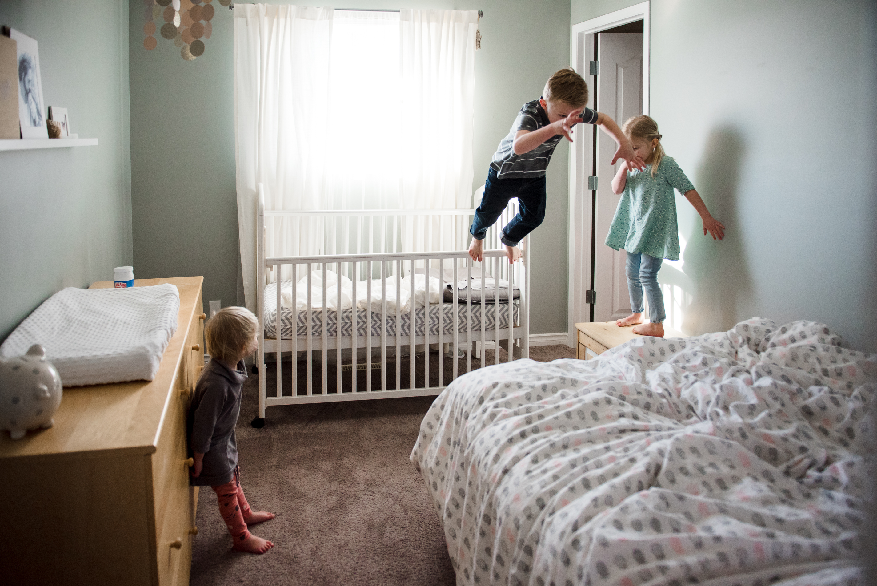 Kids jump from a crib to a bed in a home