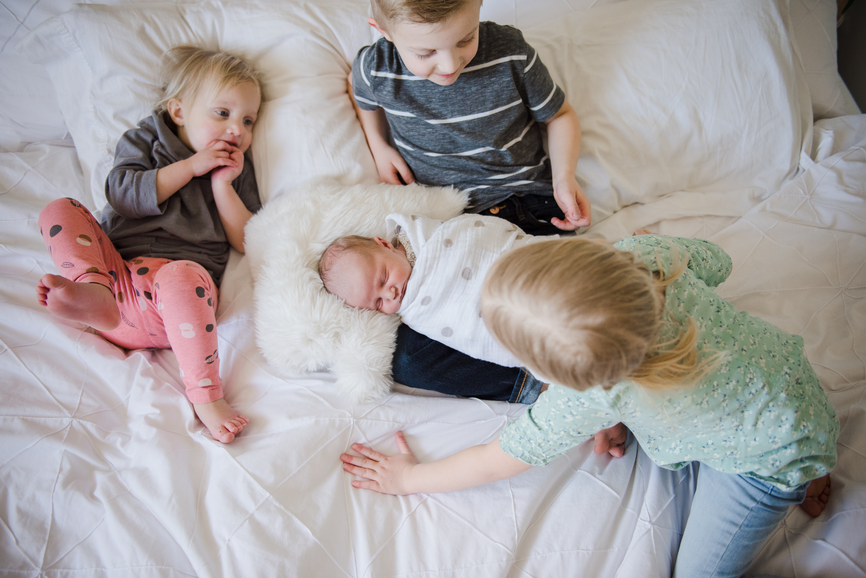 3 older siblings love on a baby in Sherwood Park while taking newborn photos