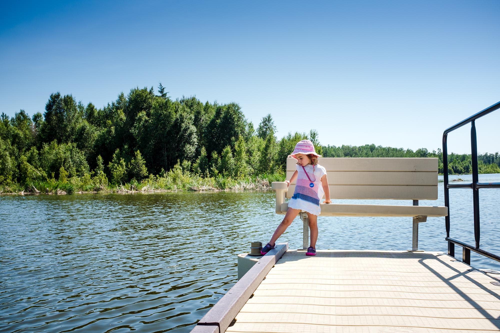 A girl sits on a bench at the end of the floating boardwalk at Elk Island National Park