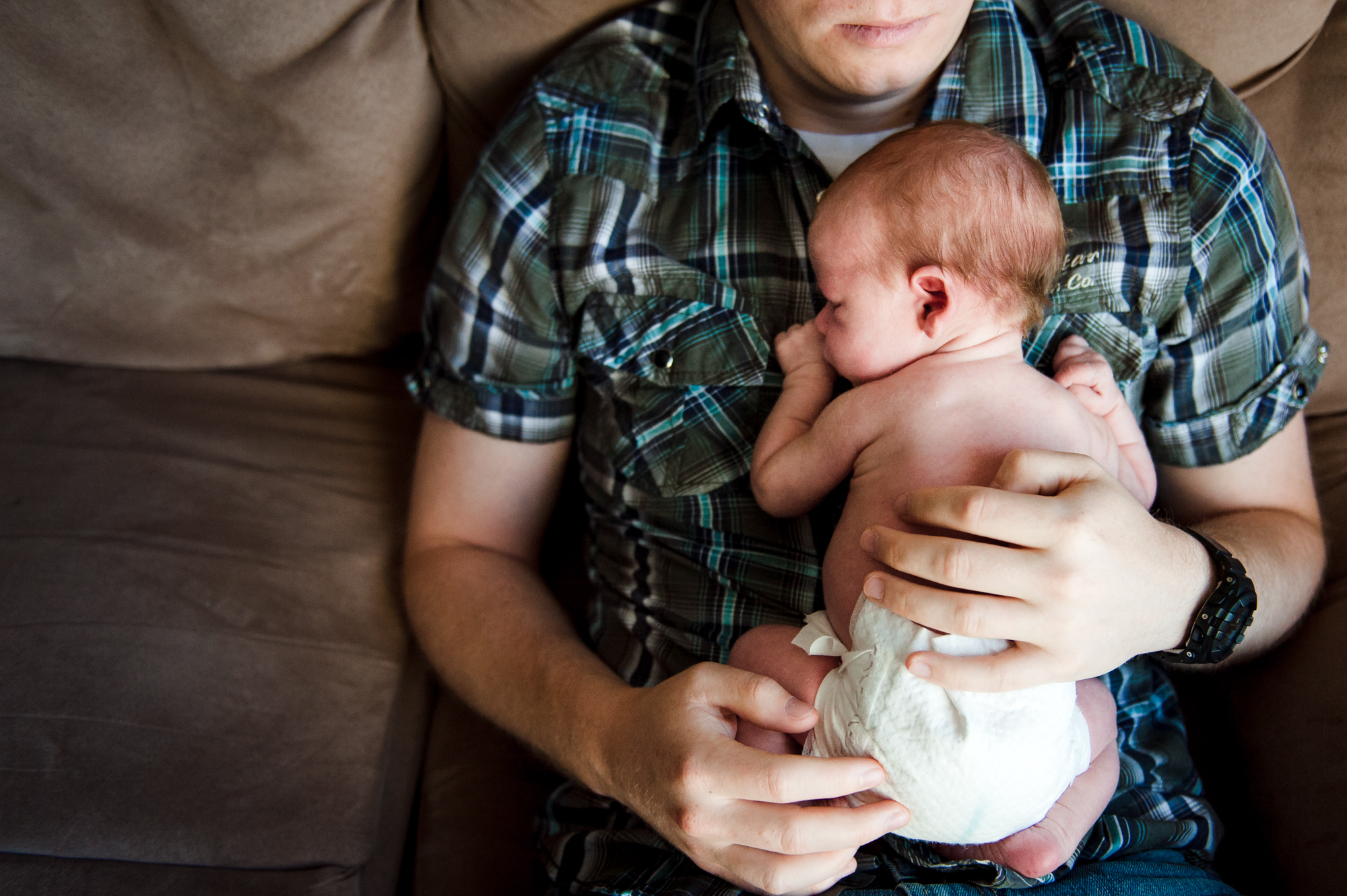 A dad cuddles his newborn daughter during an in-home newborn photo session in Edmotnon