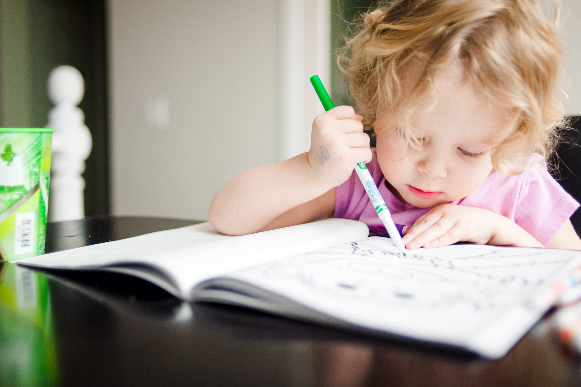 A little girl learns to print at the kitchen table