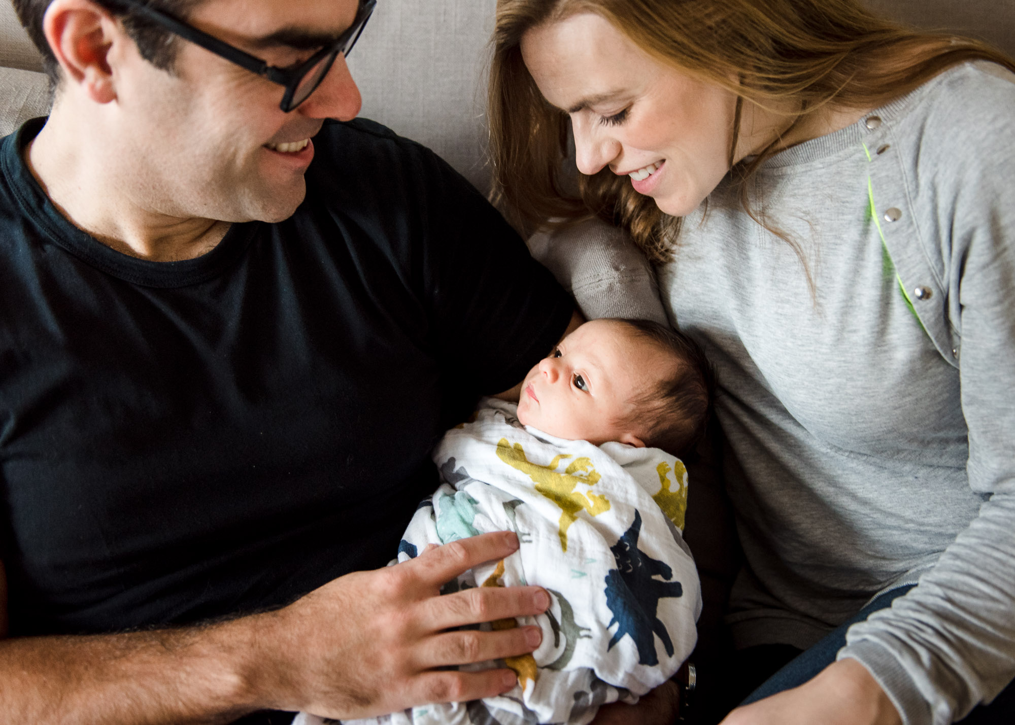 An Edmonton family cuddles on their couch during their newborn baby photo session