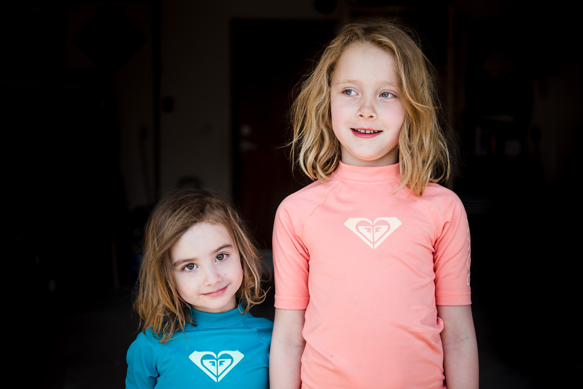 2 girls stand for a portrait using garage light. 